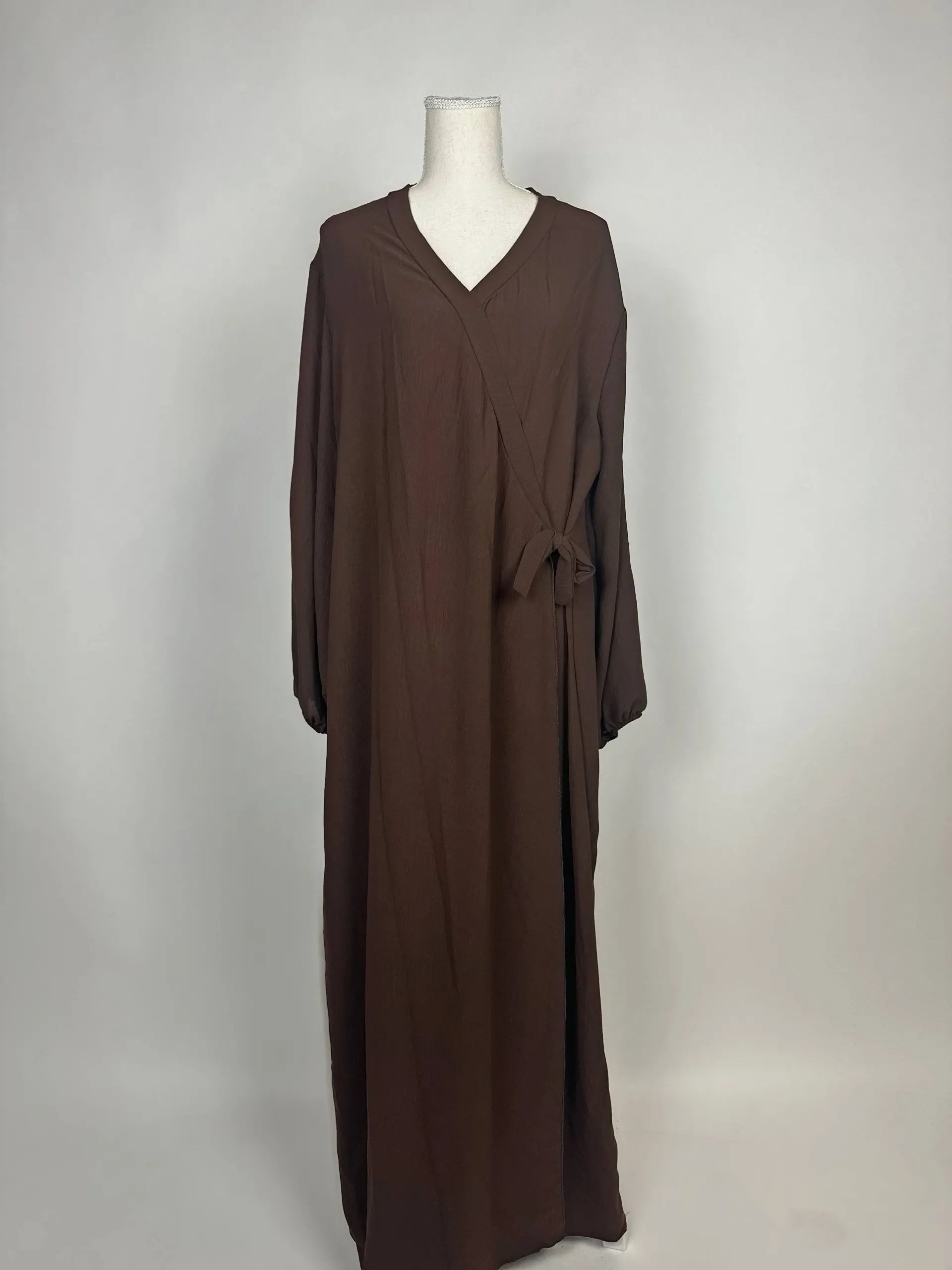 Braune Wickelabaya aus leichtem Stoff zeigt Ballonärmel und seitliche Schleife im Modest Hijab-Stil, Vorderansicht.