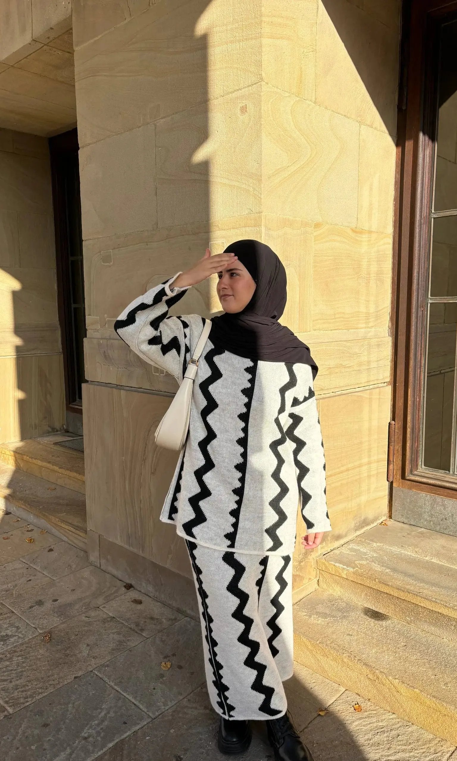 Weiß-schwarzer Zweiteiler mit Rock aus Strick mit Zickzack-Muster und langen Ärmeln, Vorderansicht.