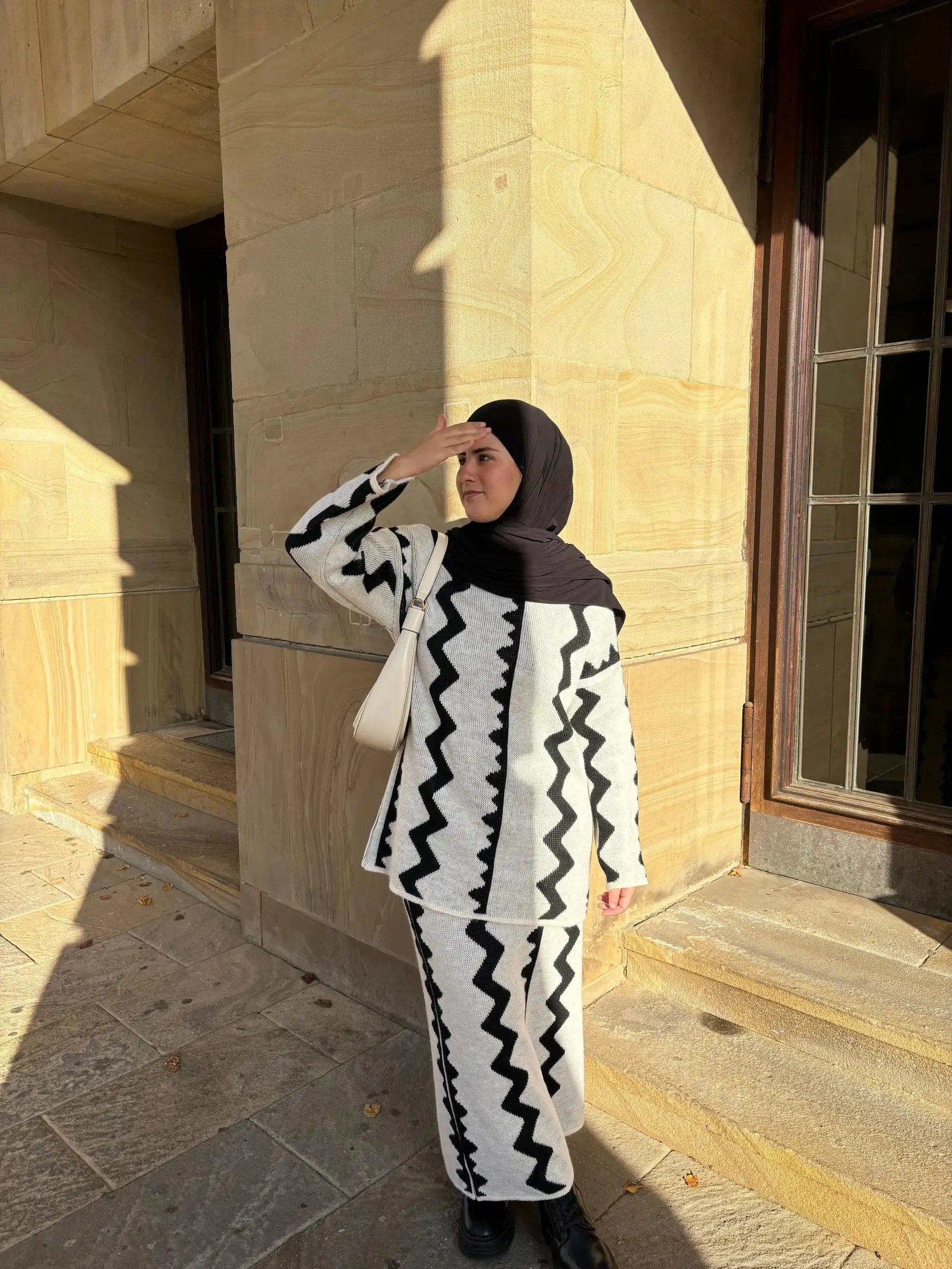 Weiß-schwarzer Zweiteiler mit Rock aus Strick mit Zickzack-Muster und langen Ärmeln, Vorderansicht.