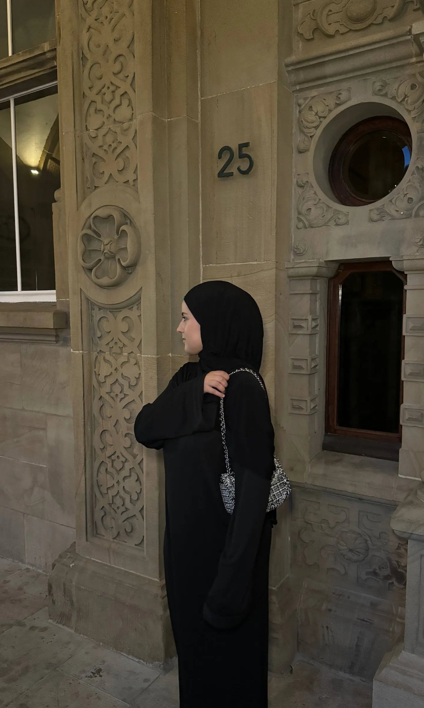 Schwarze Abaya mit gerippter Optik, bodenlang, langen, weiten Ärmeln, oversized, mit silberner Kettentasche, Seitenansicht