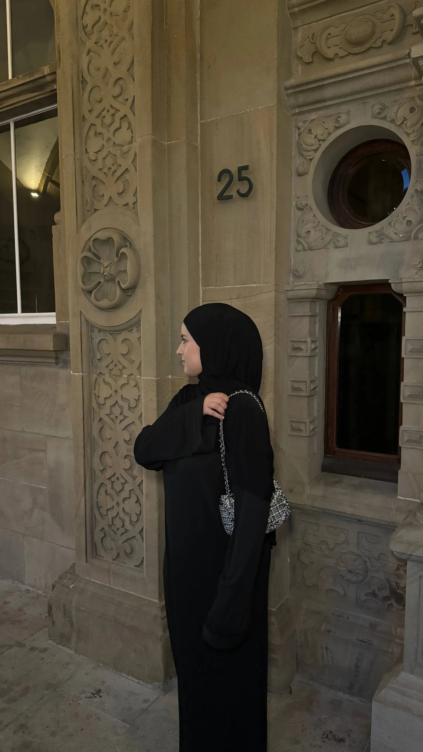 Schwarze Abaya mit gerippter Optik, bodenlang, langen, weiten Ärmeln, oversized, mit silberner Kettentasche, Seitenansicht