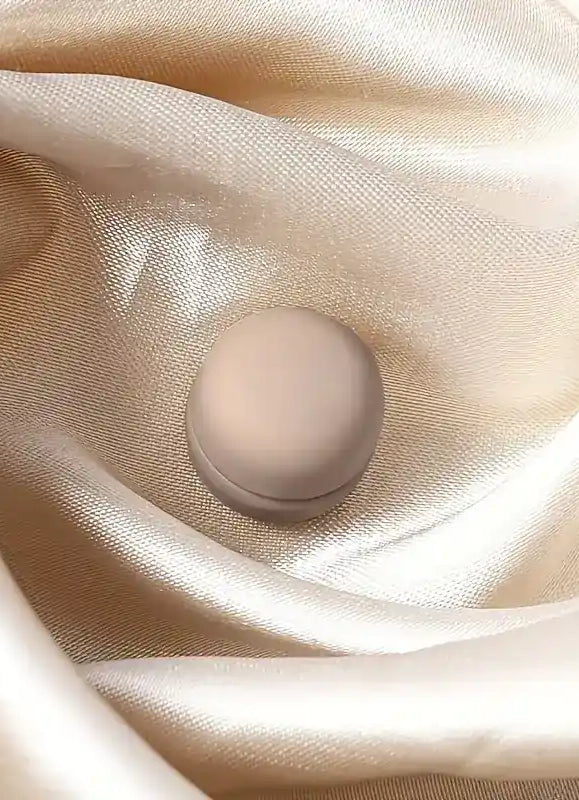 Beiger Hijab-Magnet, matt und rund, nadellos für starken Halt, auf champagnerfarbenem Satin-Hijab, Nahaufnahme