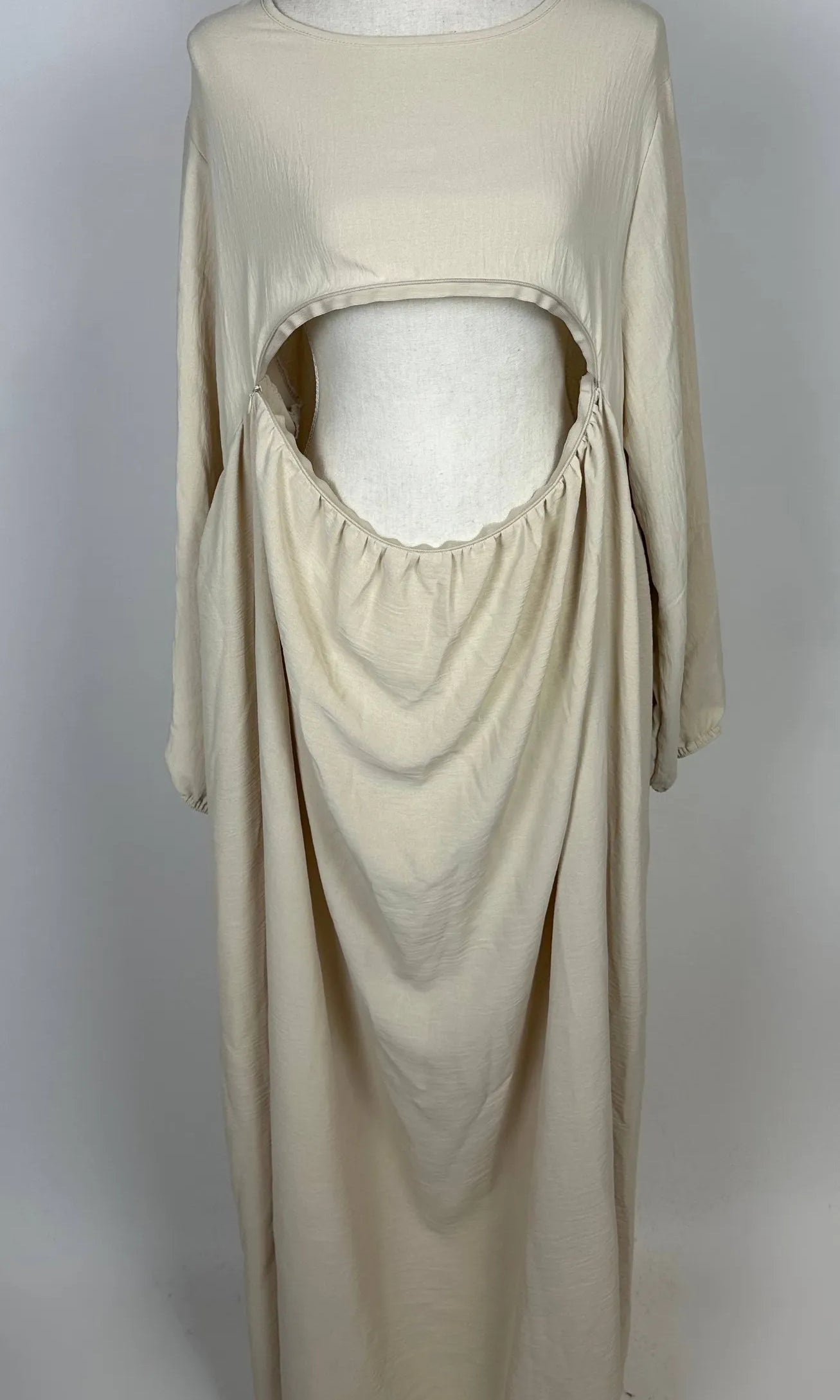 Beige Still-Abaya aus luftigem Jazzstoff mit großer Frontöffnung und Raffungen, in der Vorderansicht gezeigt.