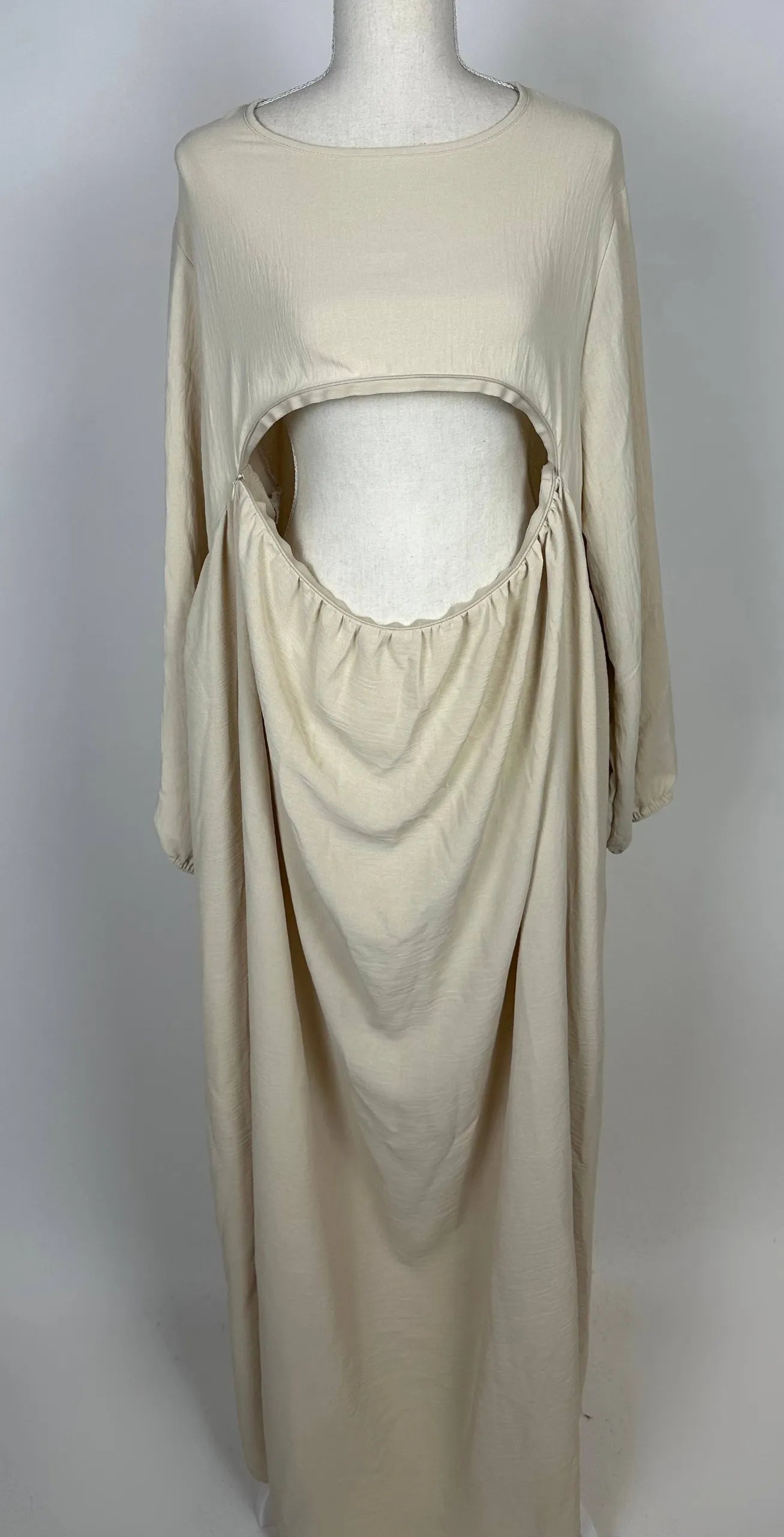 Beige Still-Abaya aus luftigem Jazzstoff mit großer Frontöffnung und Raffungen, in der Vorderansicht gezeigt.