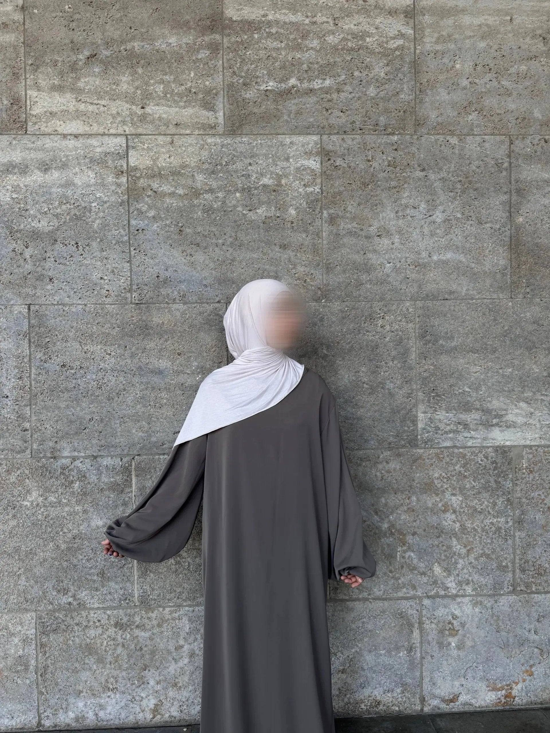 Eine graue Abaya aus Medina-Seide mit Ballonärmeln wird in der Rückansicht gezeigt.