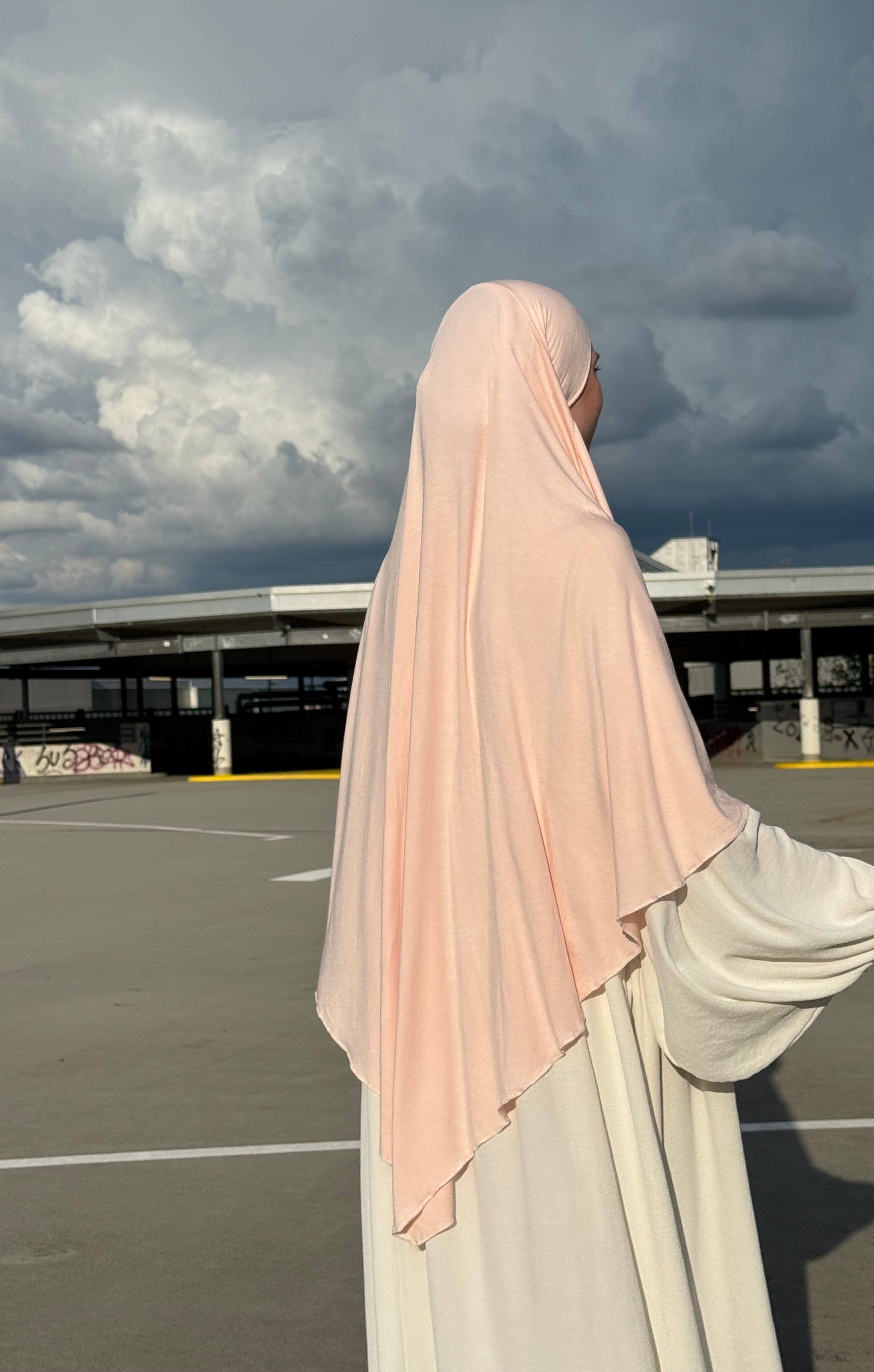 Ein Jersey Khimar in hellrosa aus Viskose-Elastan ist seitlich von hinten zu sehen.