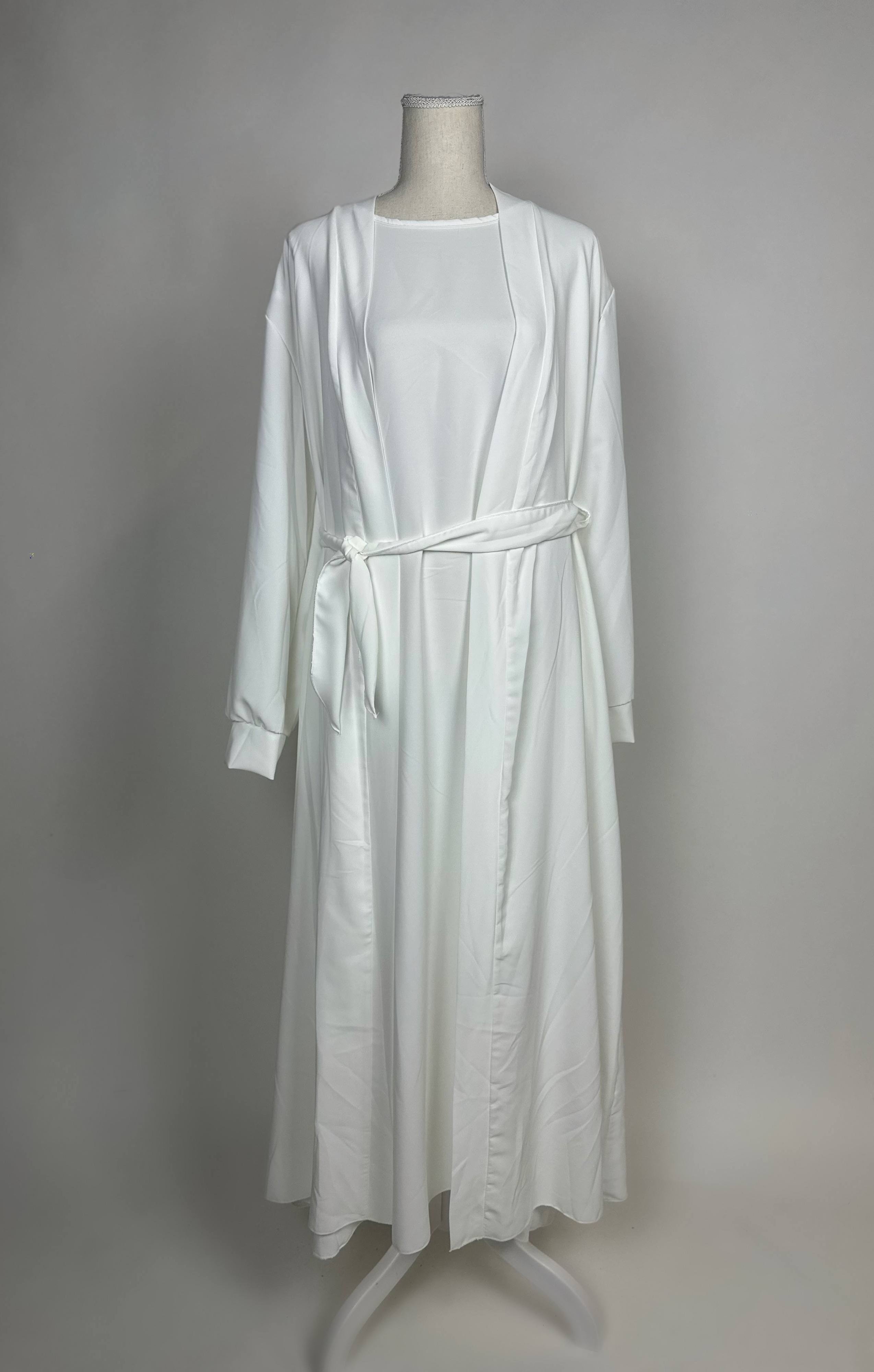 Eine weiße Open-Abaya im Dubai-Stil aus Medina-Seide mit Unterkleid und Bindegürtel wird in Vorderansicht gezeigt.