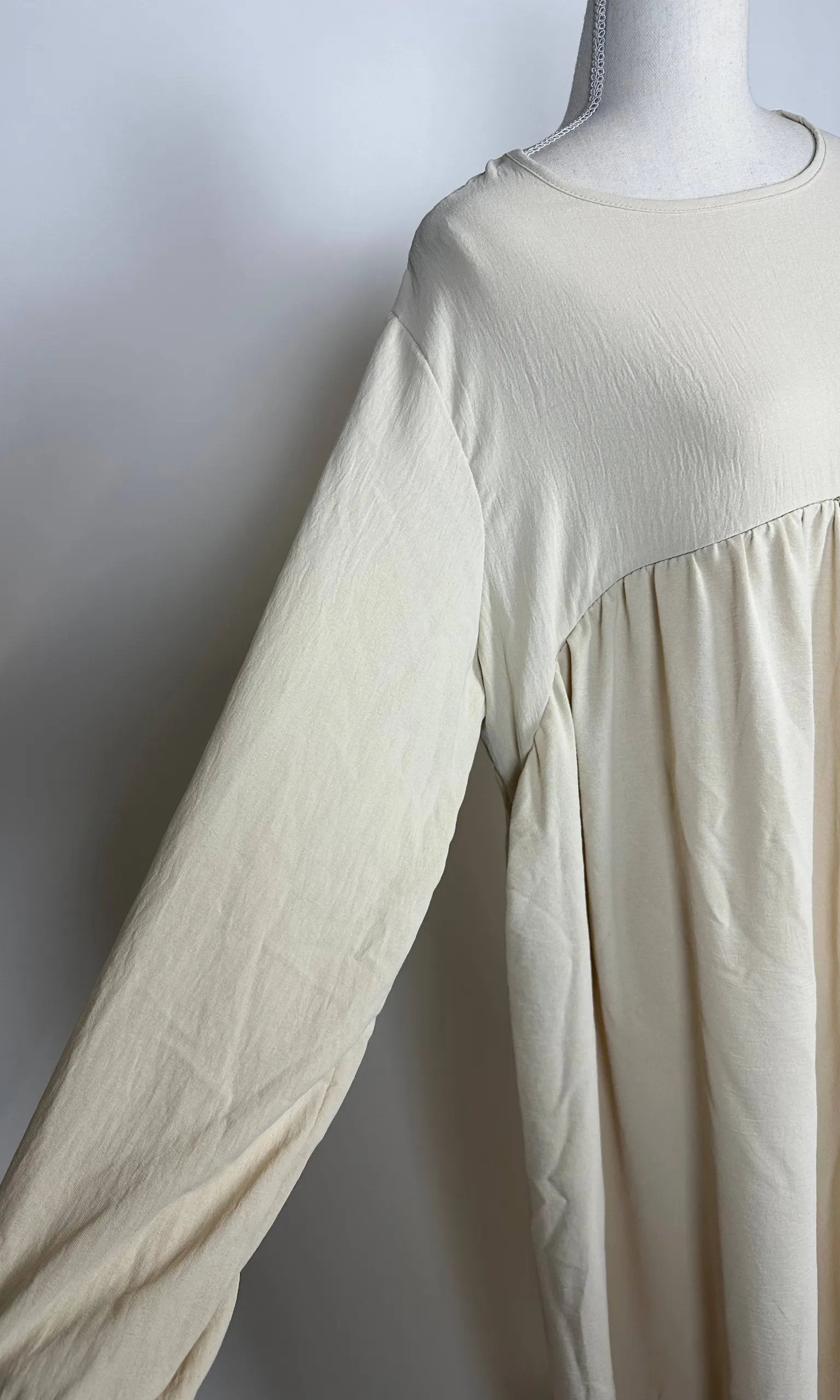 Cremefarbene Still-Abaya aus luftigem Jazzstoff mit verdeckter Stillöffnung, Detailansicht der Vorderseite.