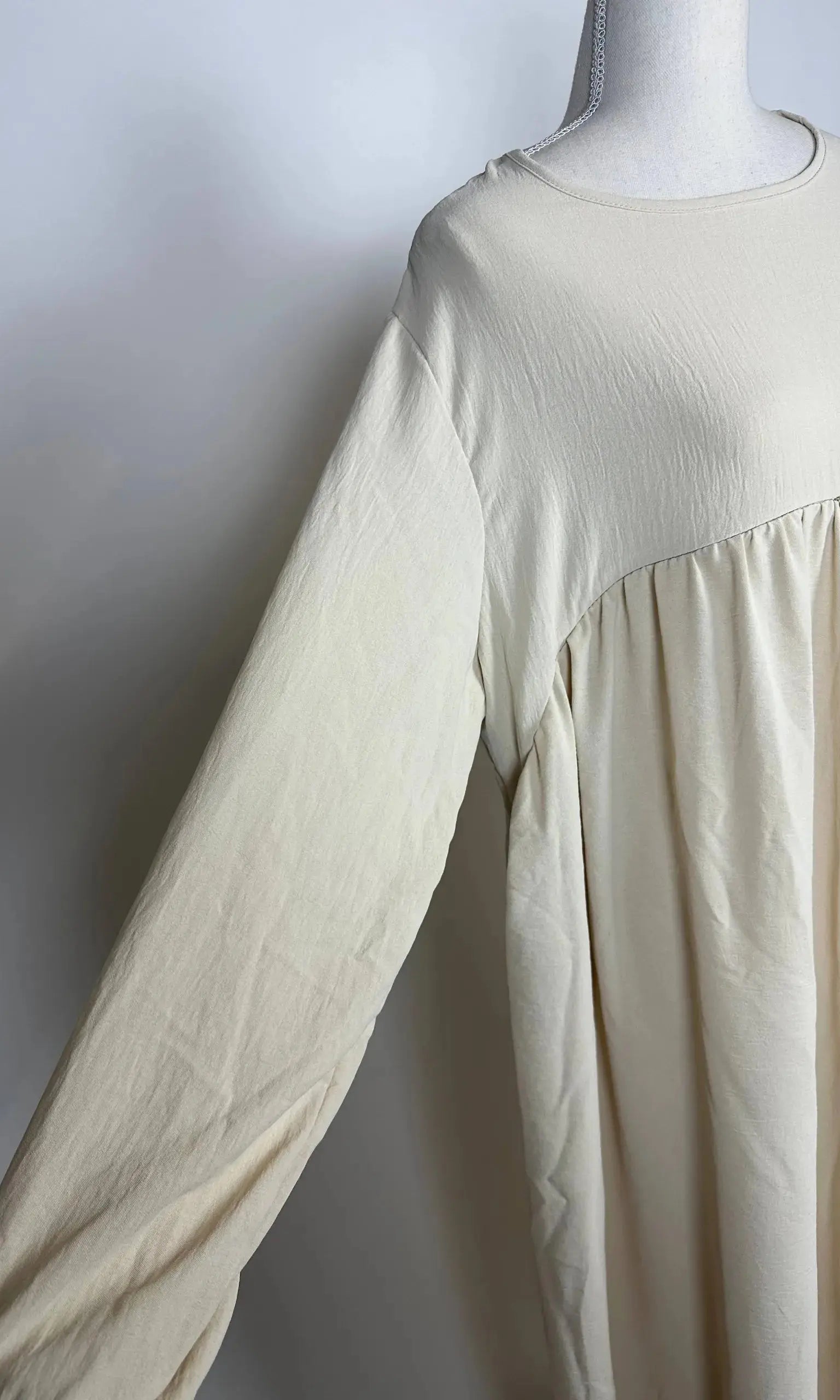 Cremefarbene Still-Abaya aus luftigem Jazzstoff mit verdeckter Stillöffnung, Detailansicht der Vorderseite.