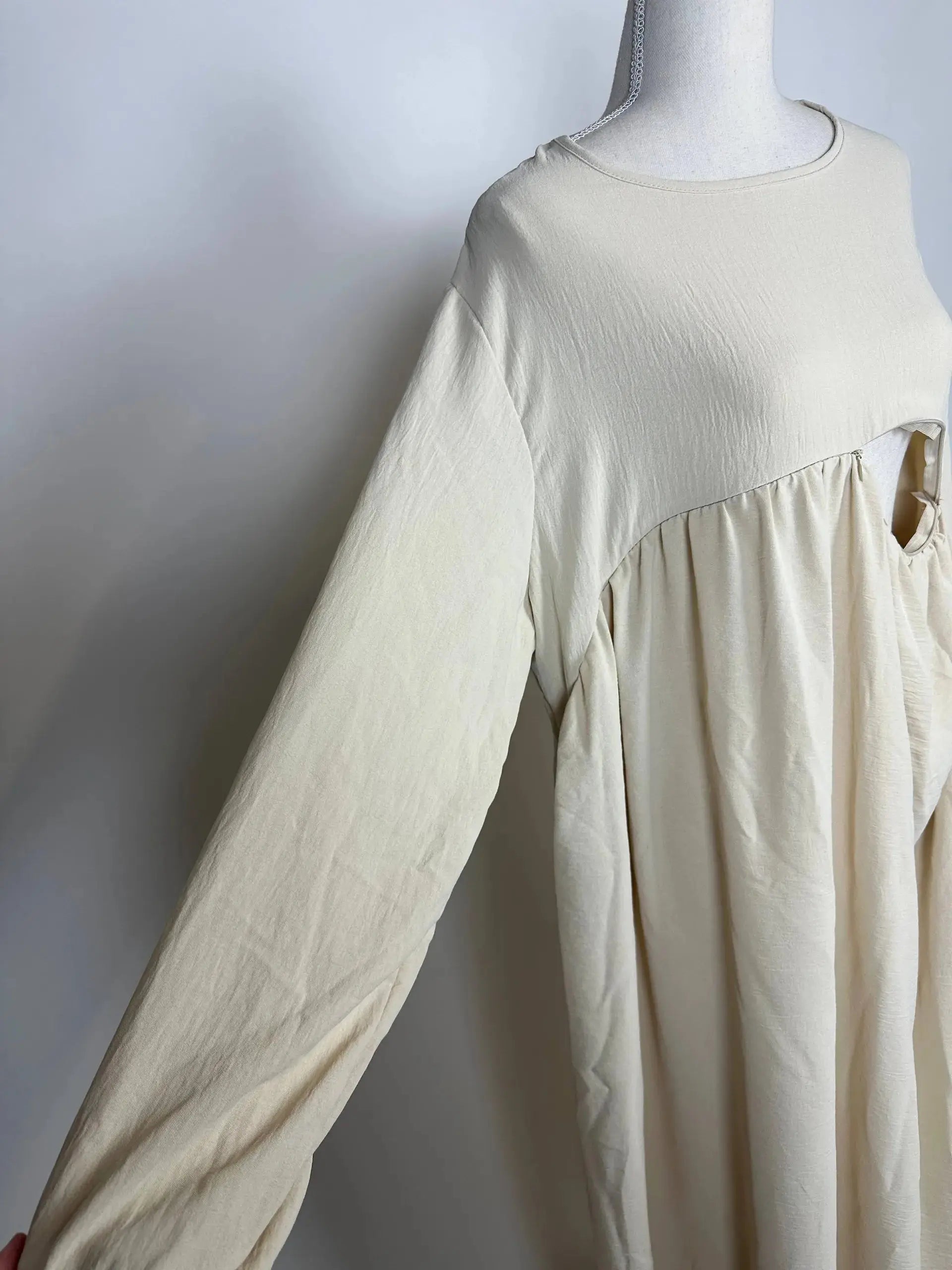 Cremefarbene Still-Abaya aus luftigem Jazzstoff mit verdeckter Stillöffnung, Detailansicht der Vorderseite.