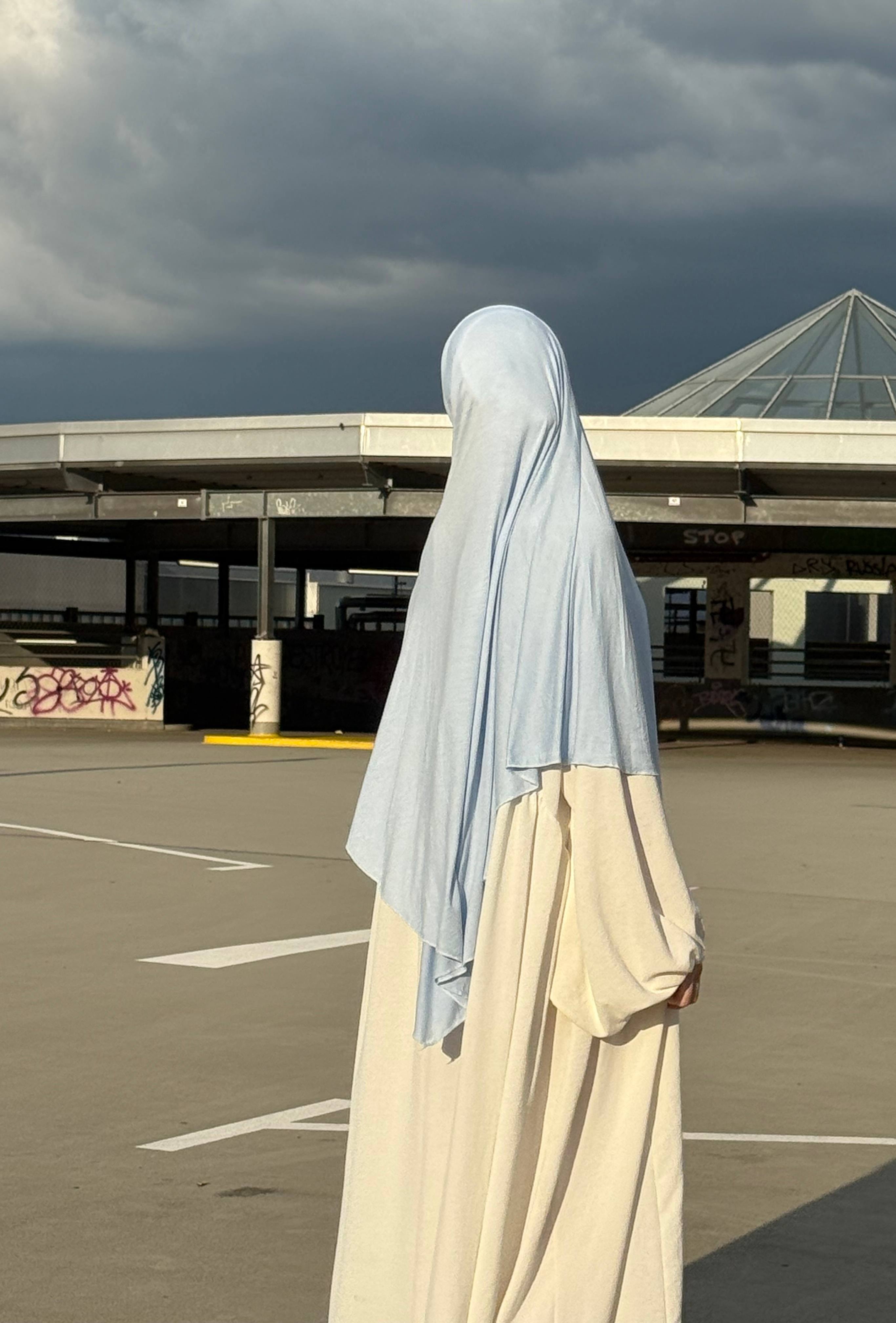 Der hellblaue Jersey Khimar aus Viskose und Elastan ist in seitlicher Rückenansicht zu sehen.