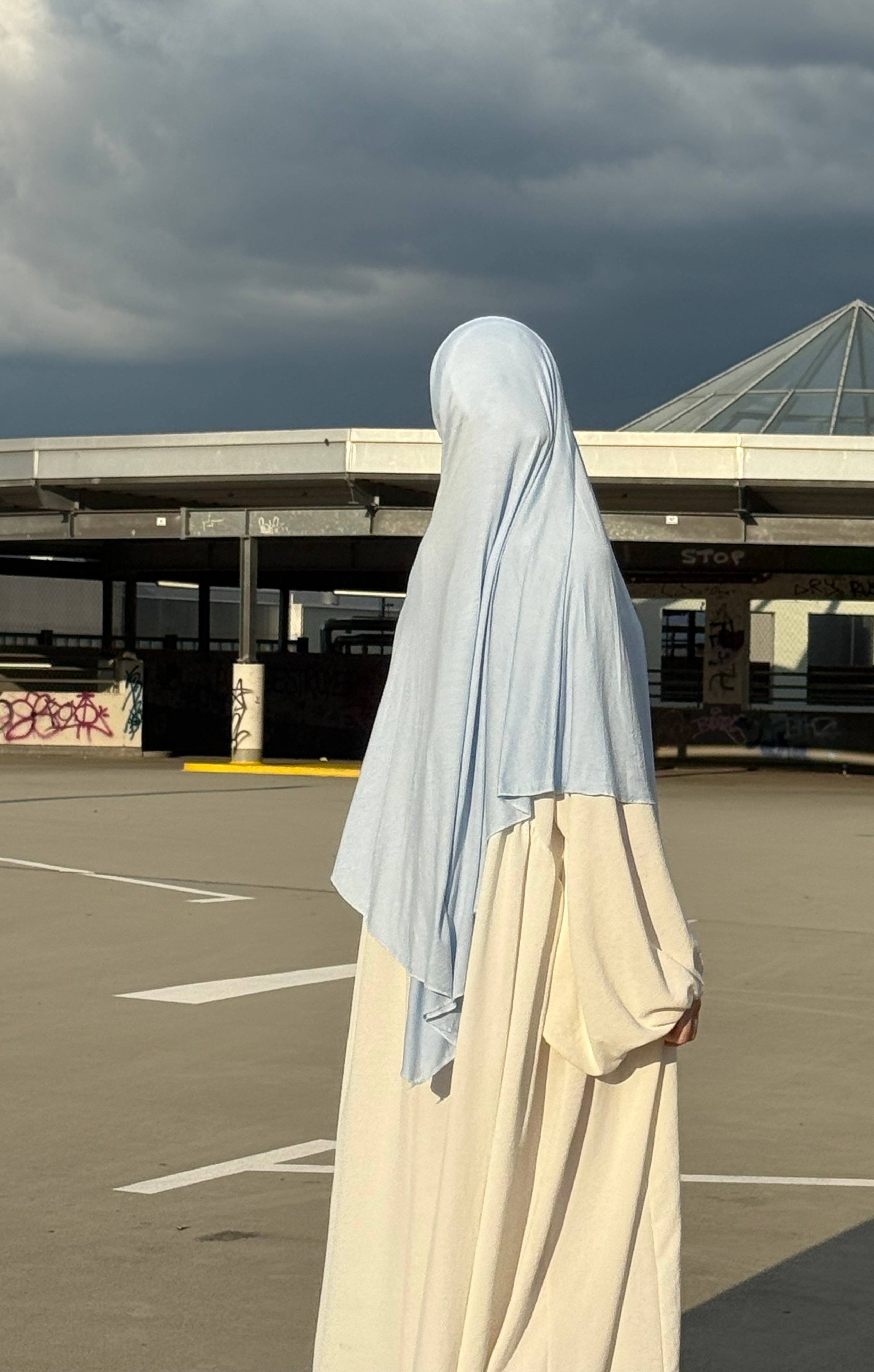 Der hellblaue Jersey Khimar aus Viskose und Elastan ist in seitlicher Rückenansicht zu sehen.