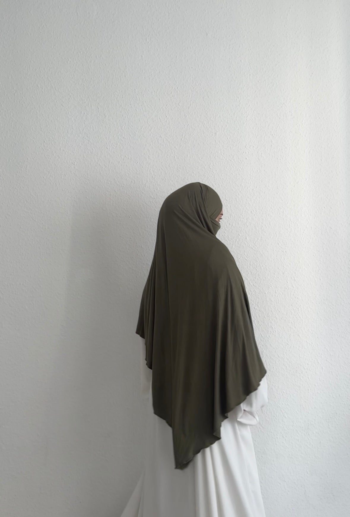 Jersey Khimar in Olivgrün aus Viskose-Elastan, seitliche Rückansicht mit Gesicht im Profil.