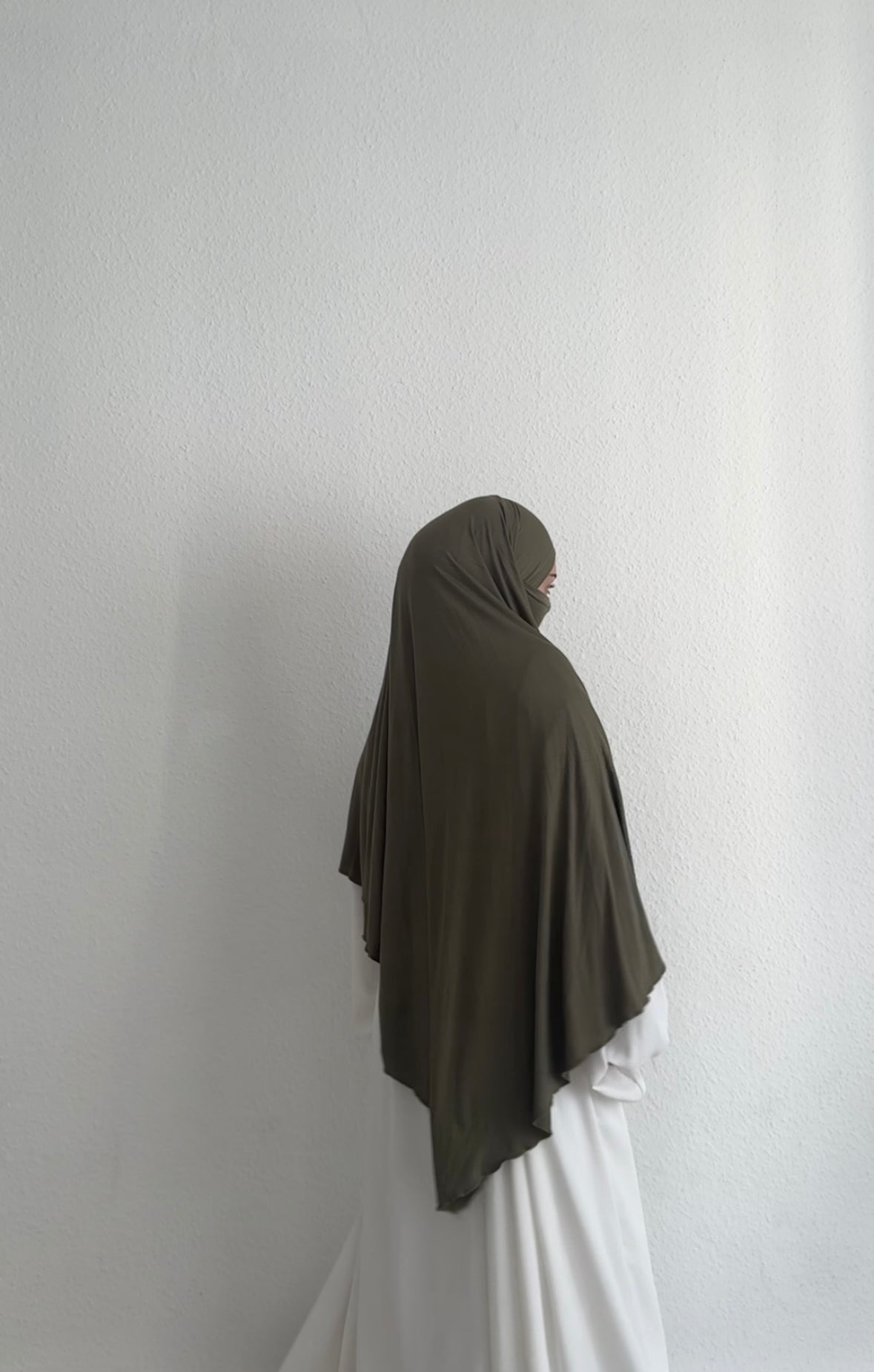 Jersey Khimar in Olivgrün aus Viskose-Elastan, seitliche Rückansicht mit Gesicht im Profil.
