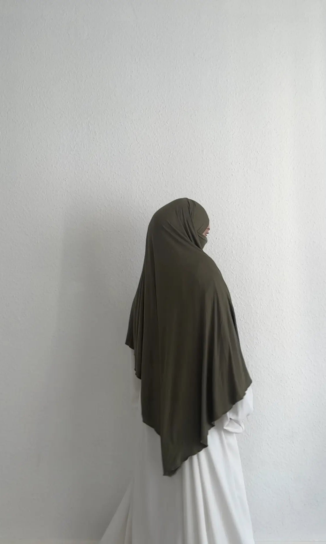 Jersey Khimar in Olivgrün aus Viskose-Elastan, seitliche Rückansicht mit Gesicht im Profil.