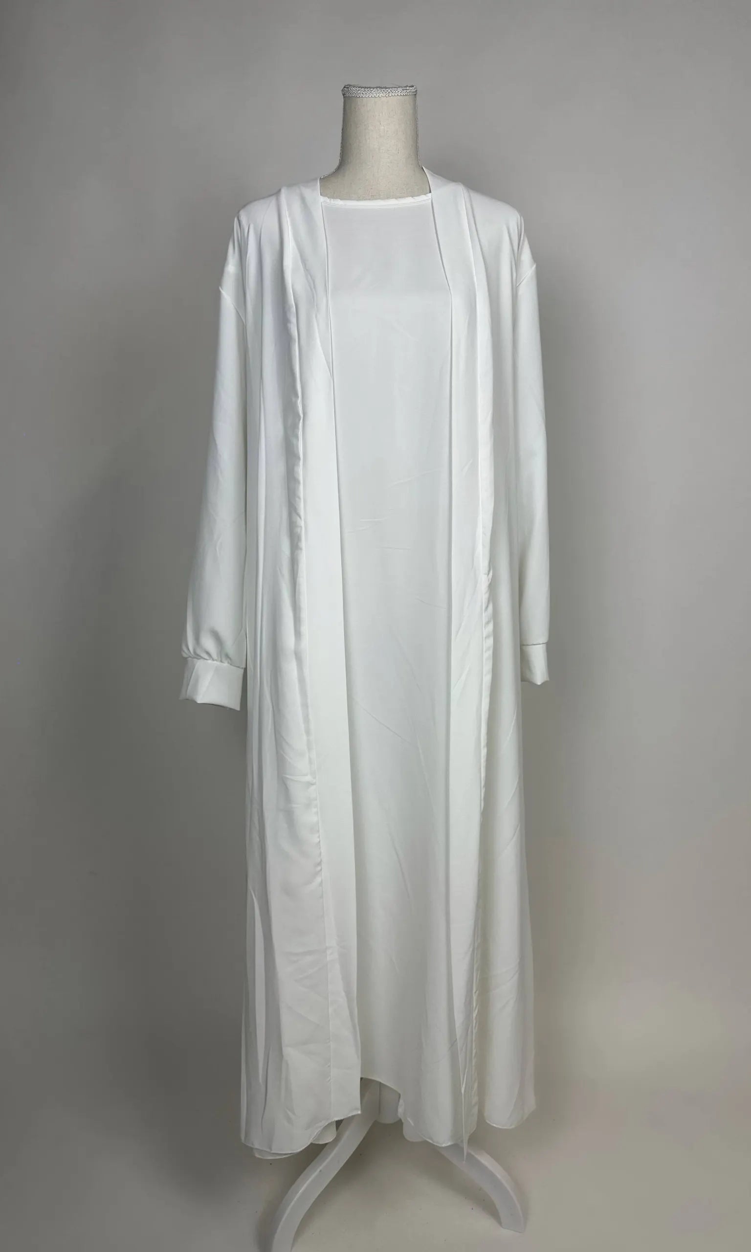 Weiße Open-Abaya Dubai aus Medina-Seide mit passendem Unterkleid ist in Vorderansicht zu sehen.
