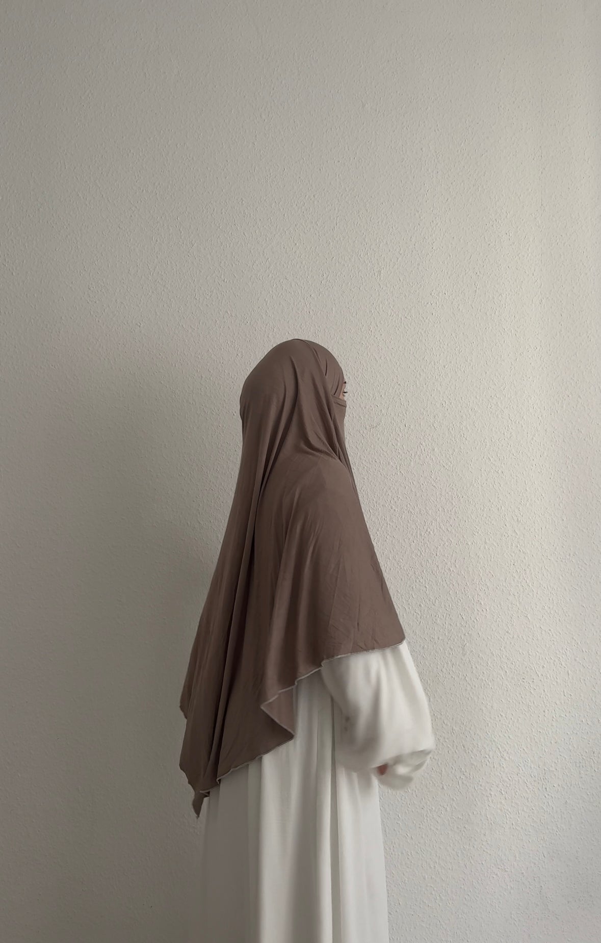 Jersey Khimar aus Viskose‑Elastan in Taupe, seitliche Ansicht an einer stehenden Person.
