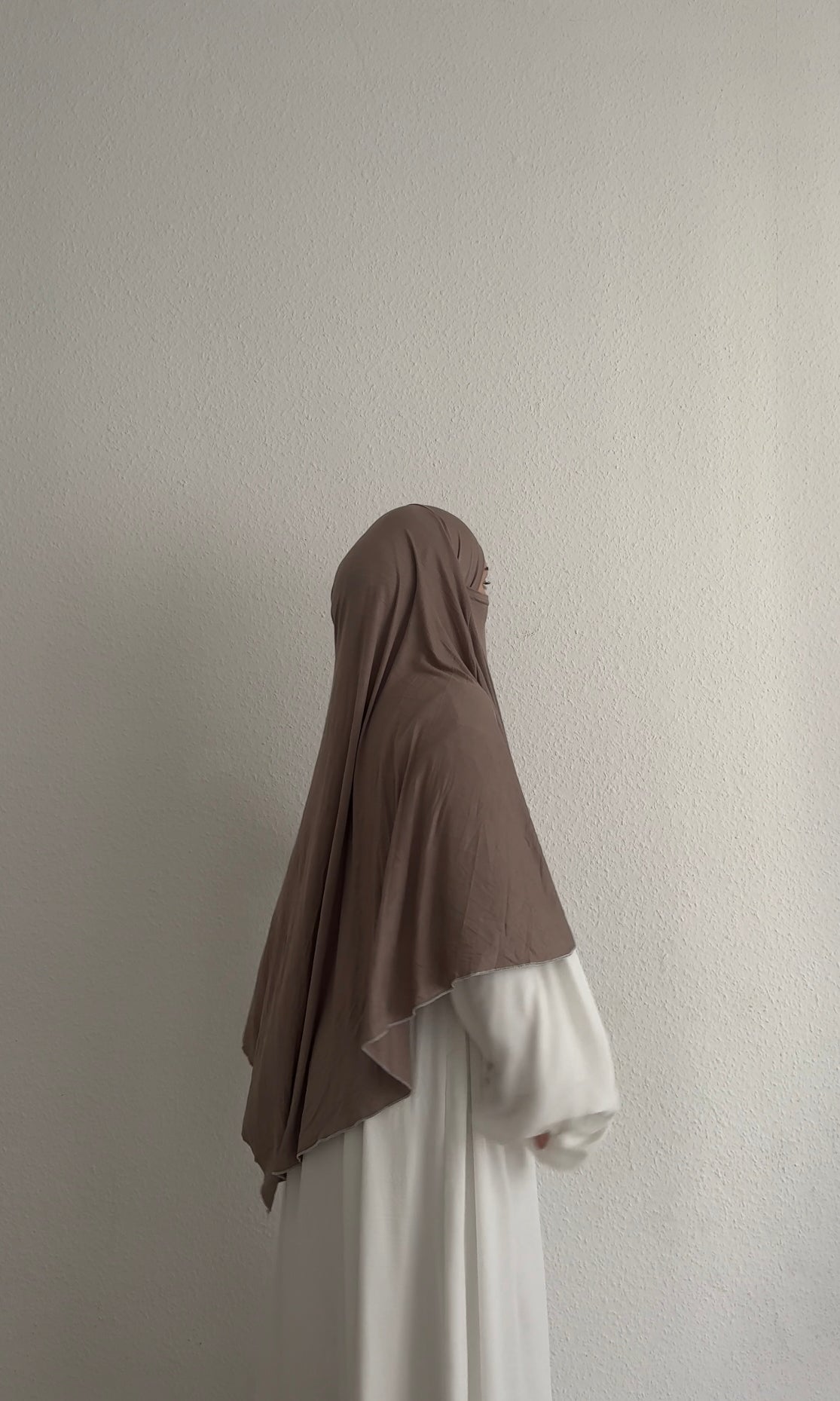 Jersey Khimar aus Viskose‑Elastan in Taupe, seitliche Ansicht an einer stehenden Person.