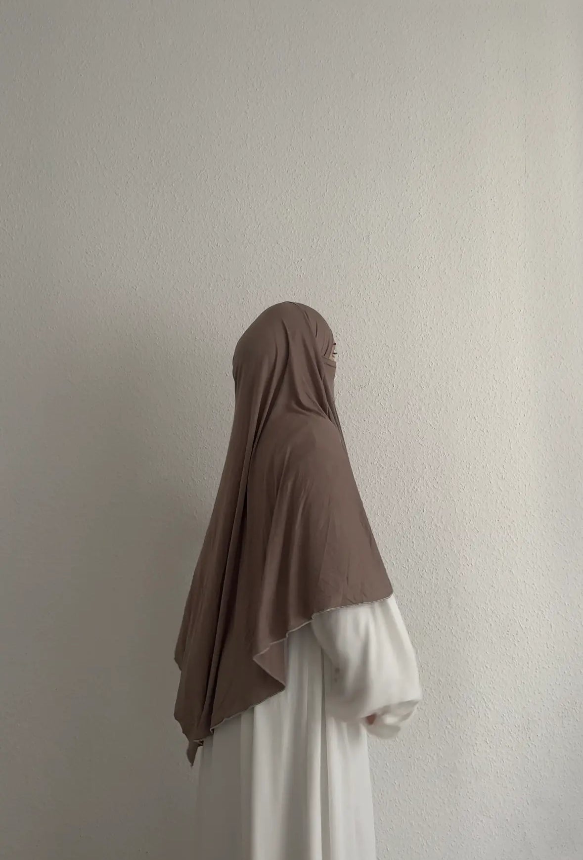 Jersey Khimar aus Viskose‑Elastan in Taupe, seitliche Ansicht an einer stehenden Person.