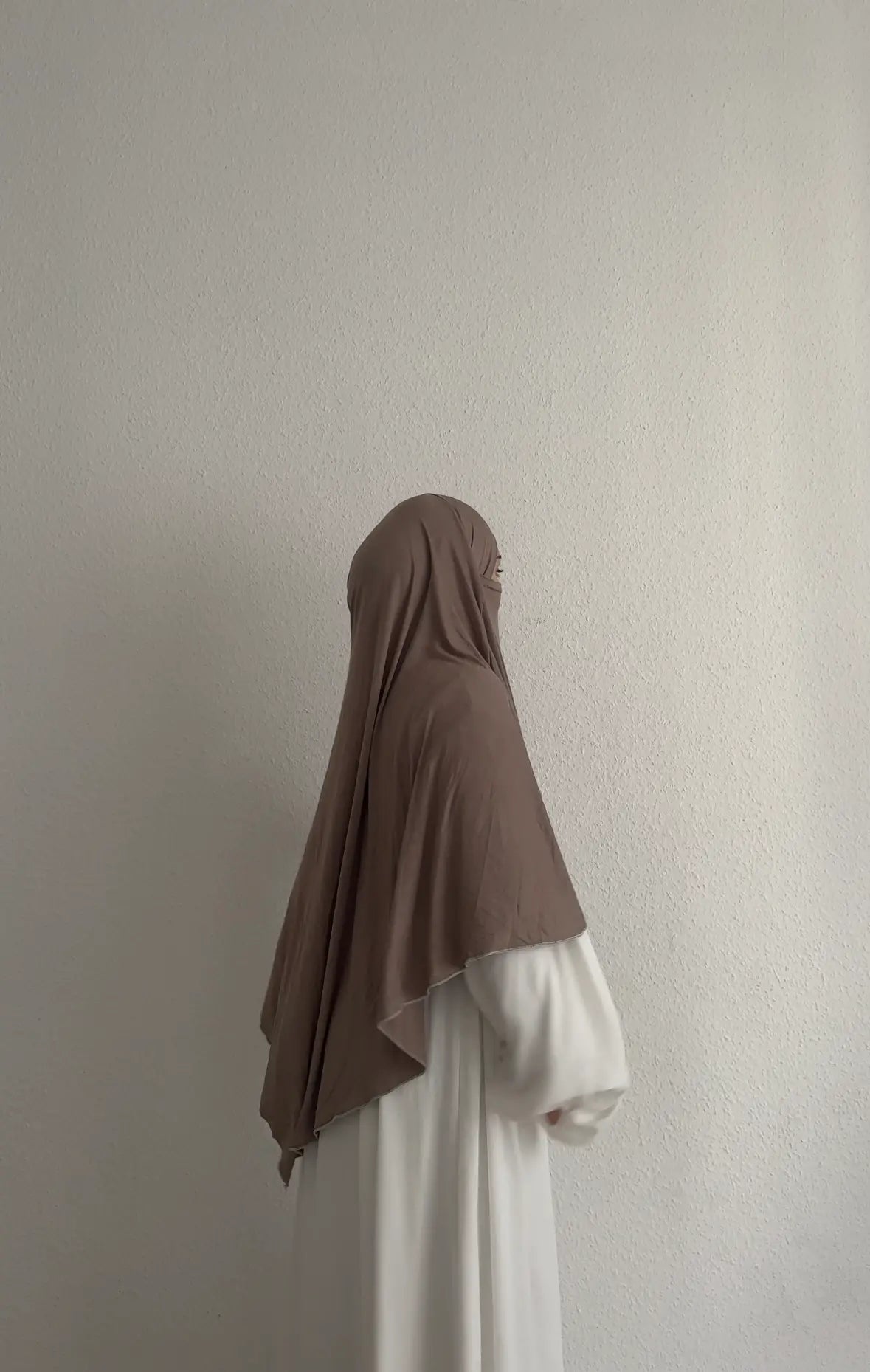 Jersey Khimar aus Viskose‑Elastan in Taupe, seitliche Ansicht an einer stehenden Person.