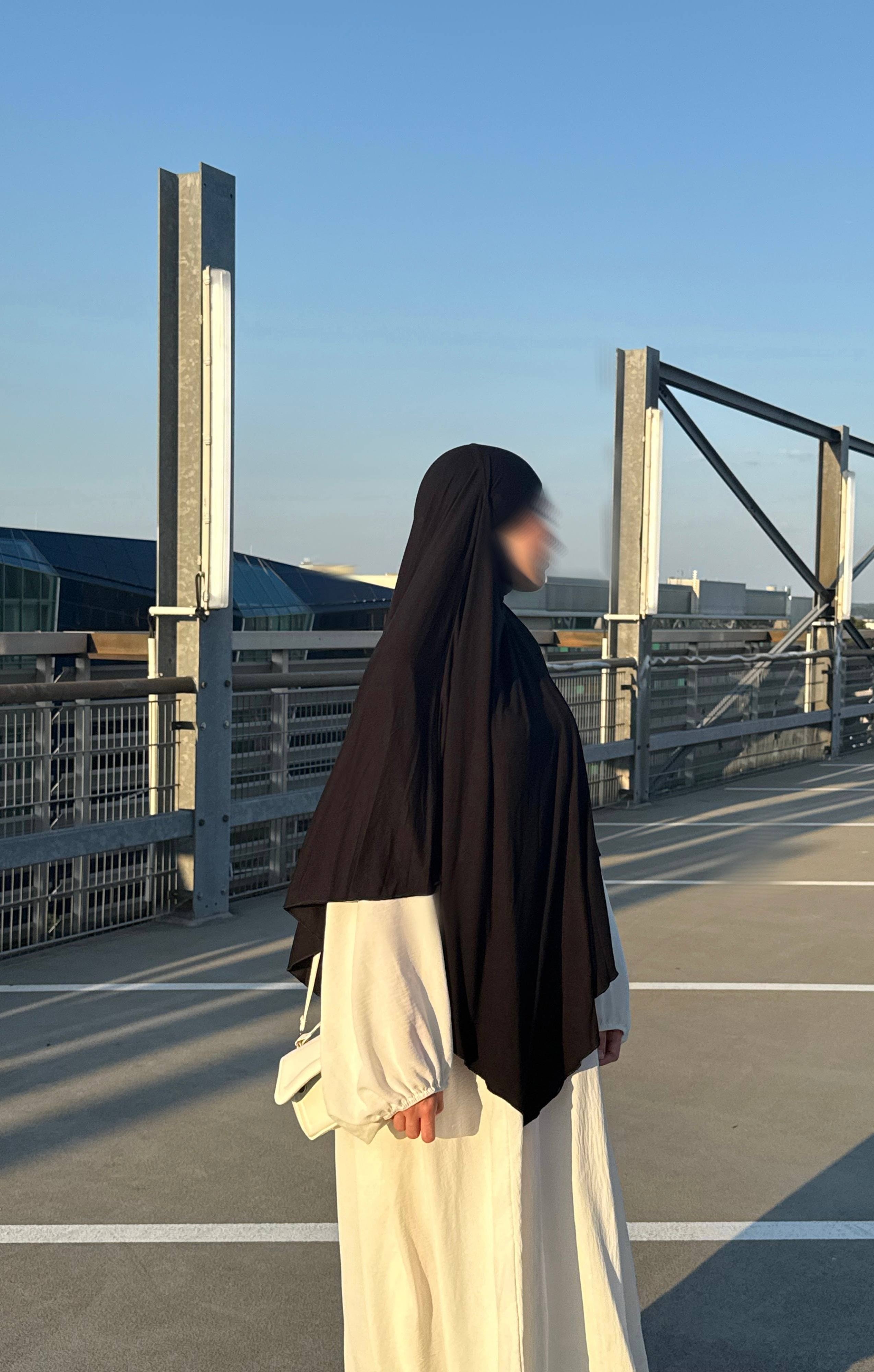 Jersey Khimar in Schwarz aus Jersey (95% Viskose, 5% Elastan), seitliche Ansicht an einer stehenden Person.
