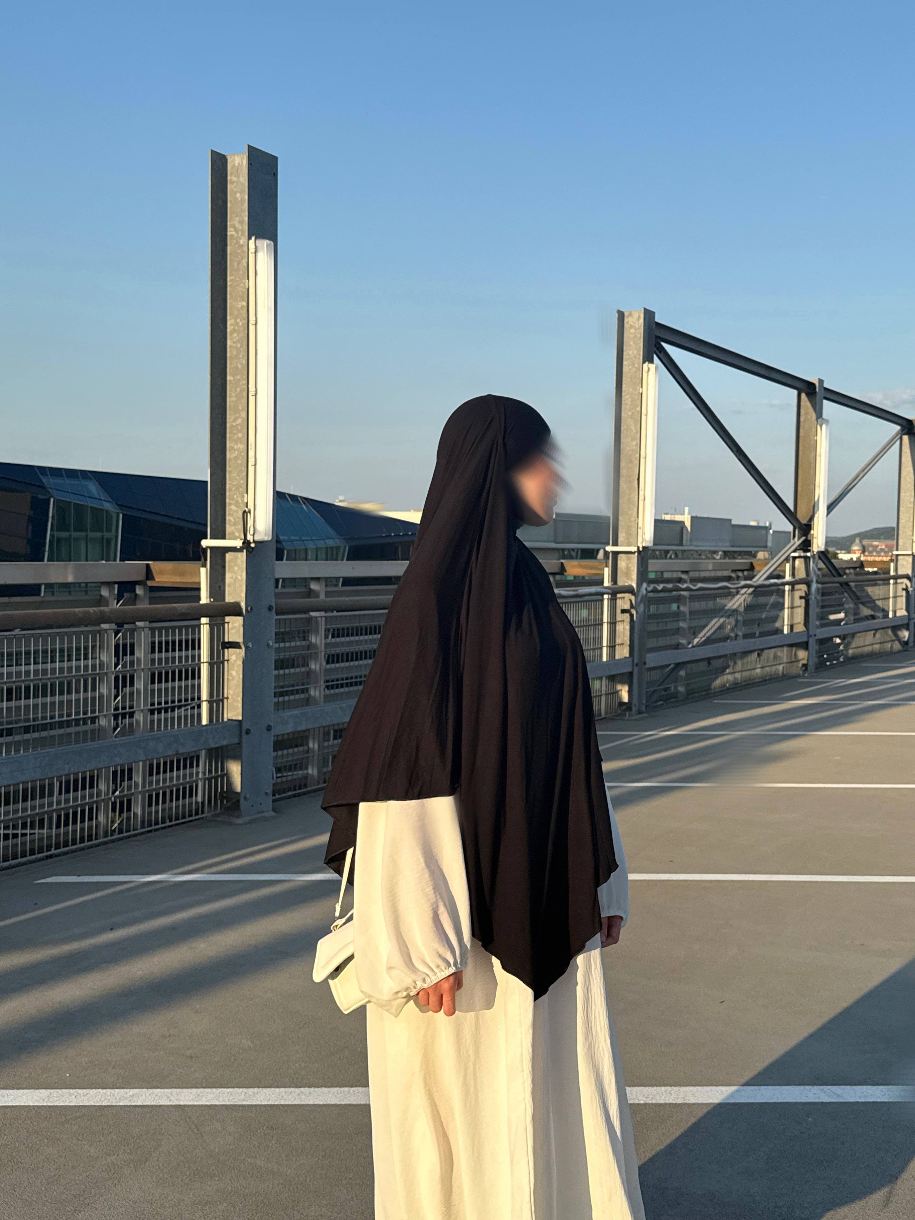 Jersey Khimar in Schwarz aus Jersey (95% Viskose, 5% Elastan), seitliche Ansicht an einer stehenden Person.