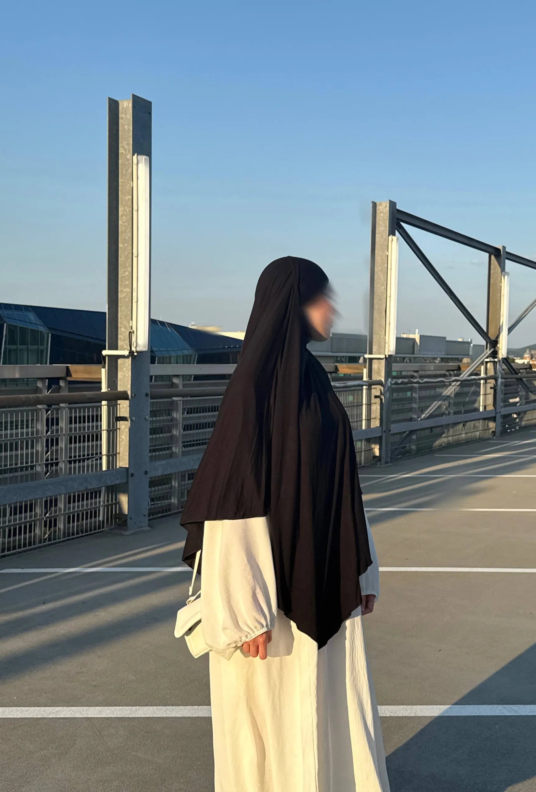 Jersey Khimar in Schwarz aus Jersey (95% Viskose, 5% Elastan), seitliche Ansicht an einer stehenden Person.