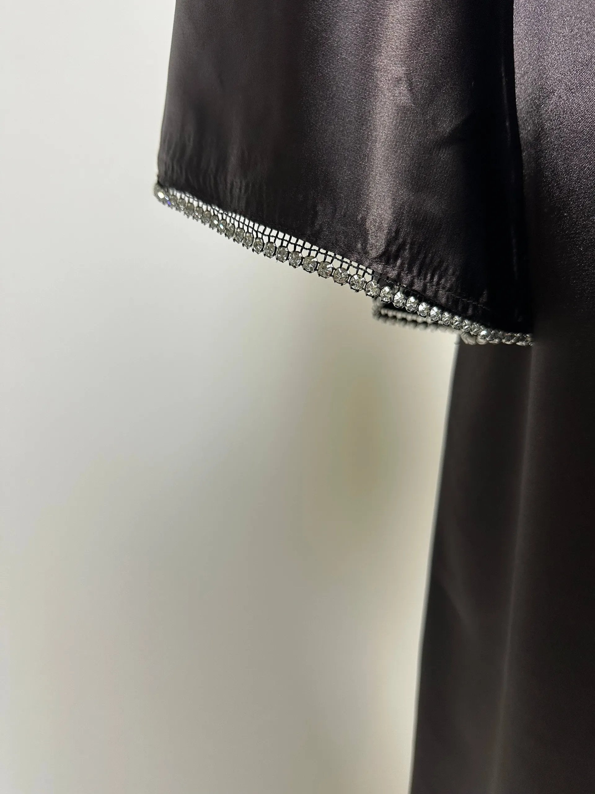 Schwarze Abaya aus satinartigem Polyester mit Strassbesatz am Ärmelsaum, Detailaufnahme