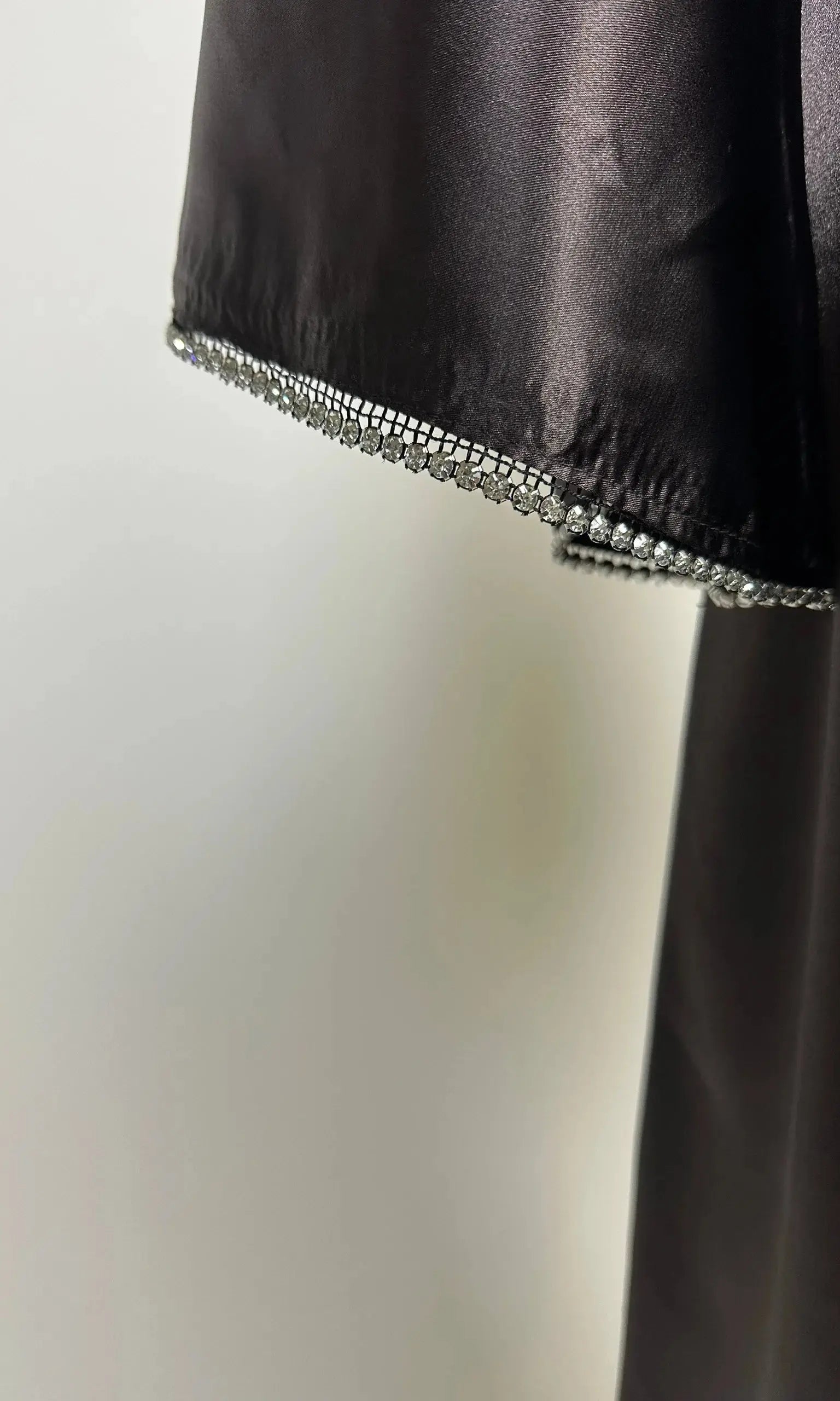 Schwarze Abaya aus satinartigem Polyester mit Strassbesatz am Ärmelsaum, Detailaufnahme