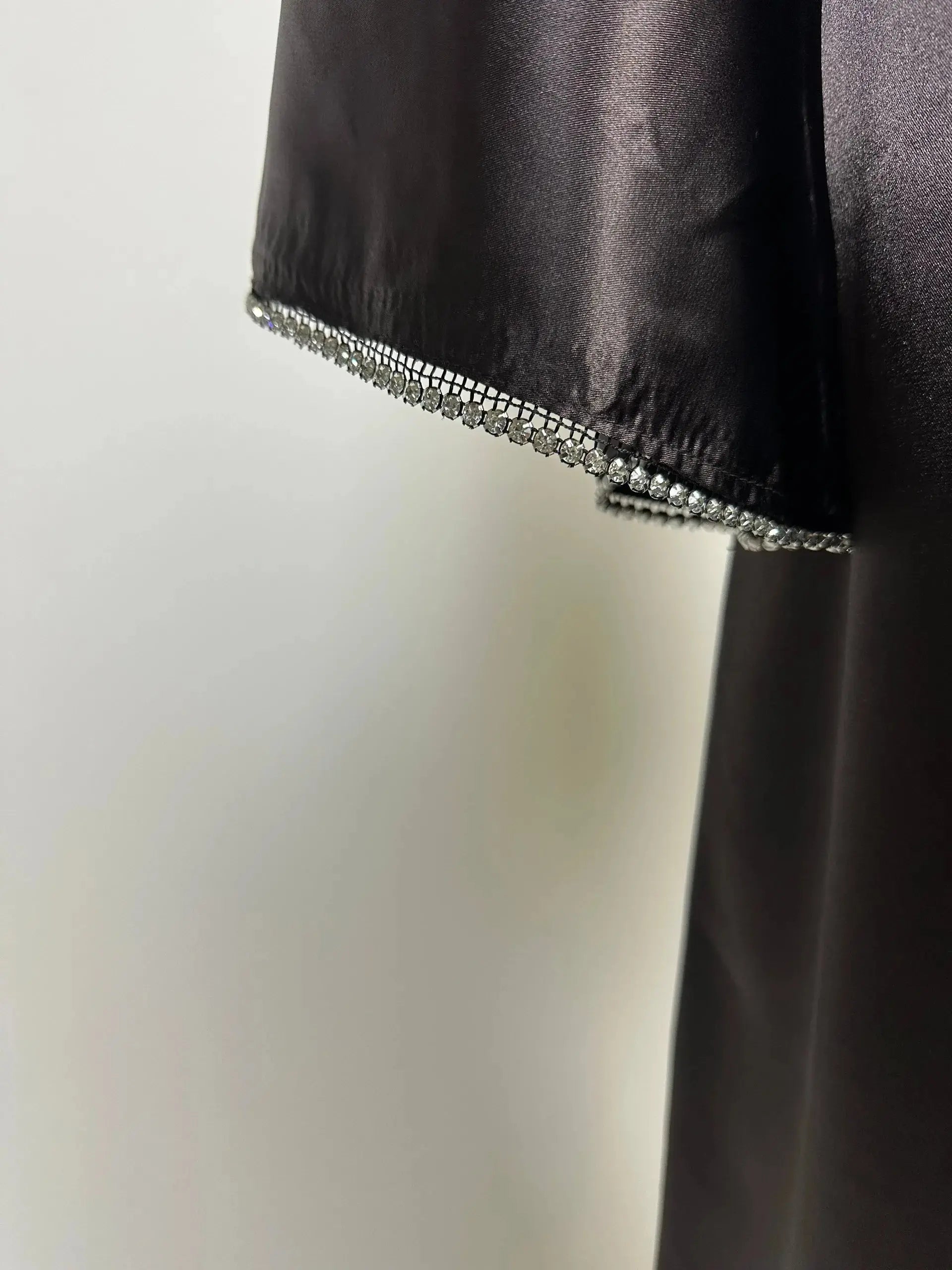 Schwarze Abaya aus satinartigem Polyester mit Strassbesatz am Ärmelsaum, Detailaufnahme