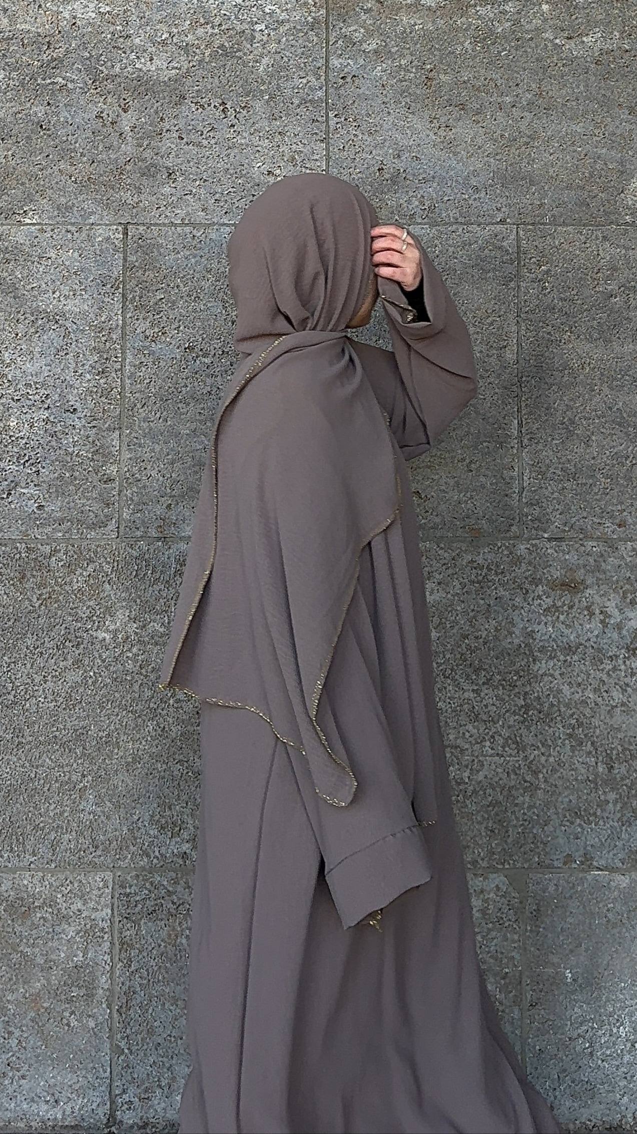 Taupefarbene Einteiler-Abaya aus fließendem Stoff mit integriertem Hijab und goldener Paspel, Seitenansicht.