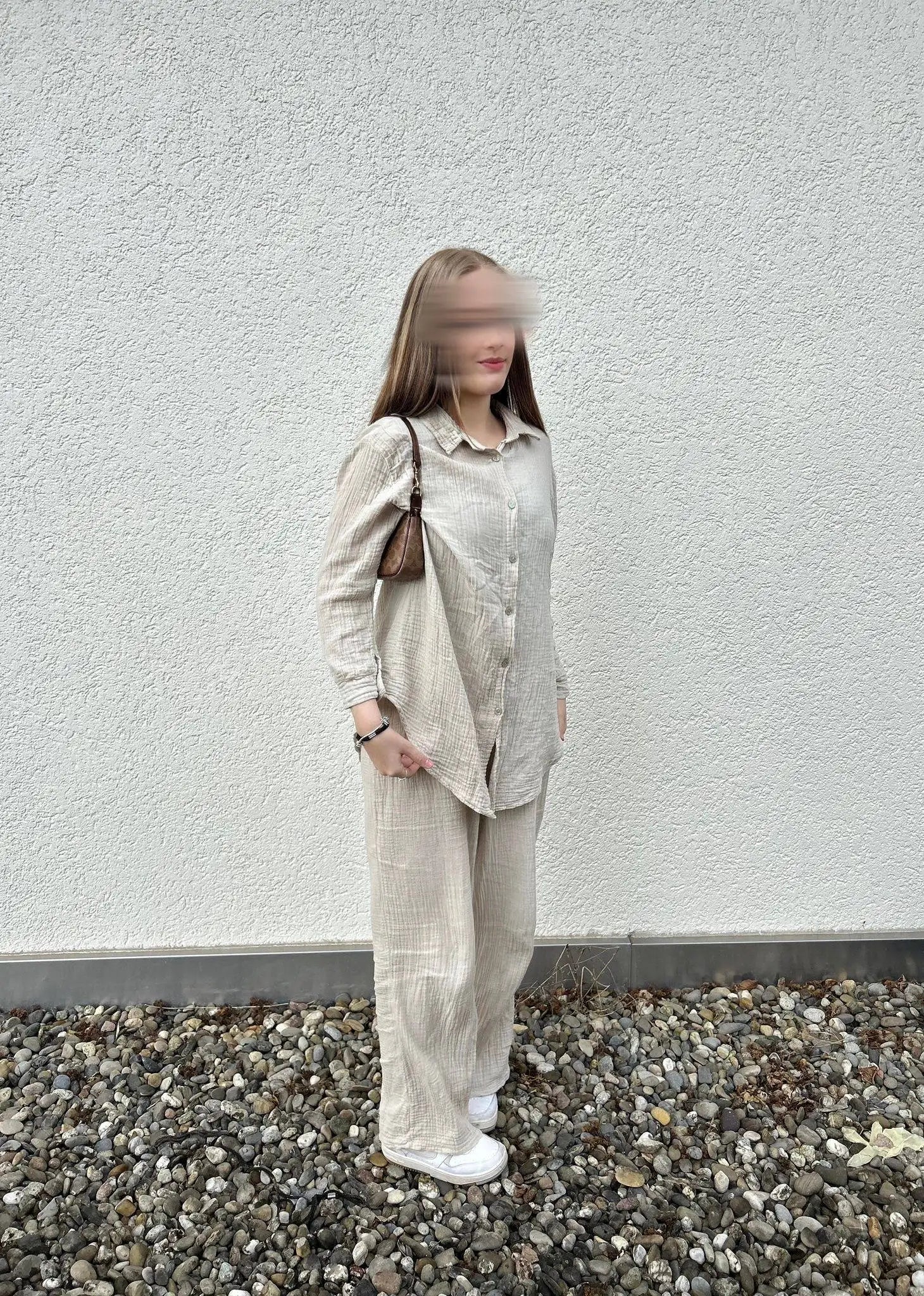 Der beige Musselin-Zweiteiler aus 100% Baumwolle mit Hemdbluse und weiter Hose ist in Seitenansicht dargestellt.
