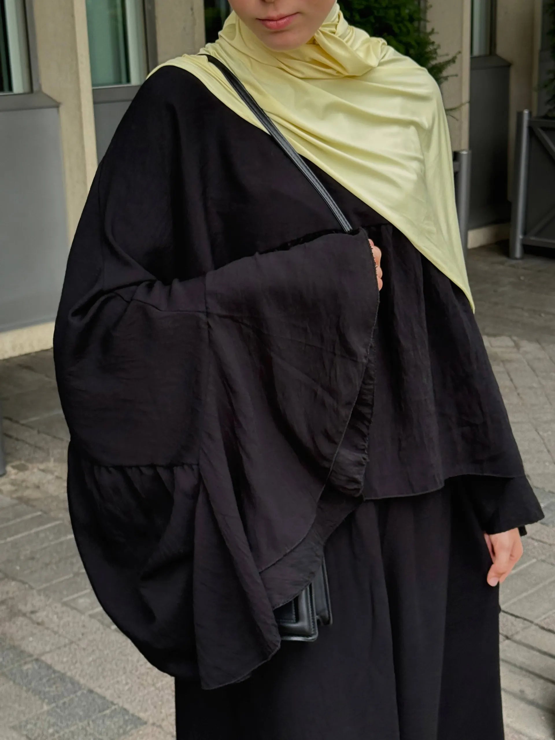 zweiteiler in schwarz mit fließendem top, weiten fledermausärmeln und maxirock, nahe frontansicht