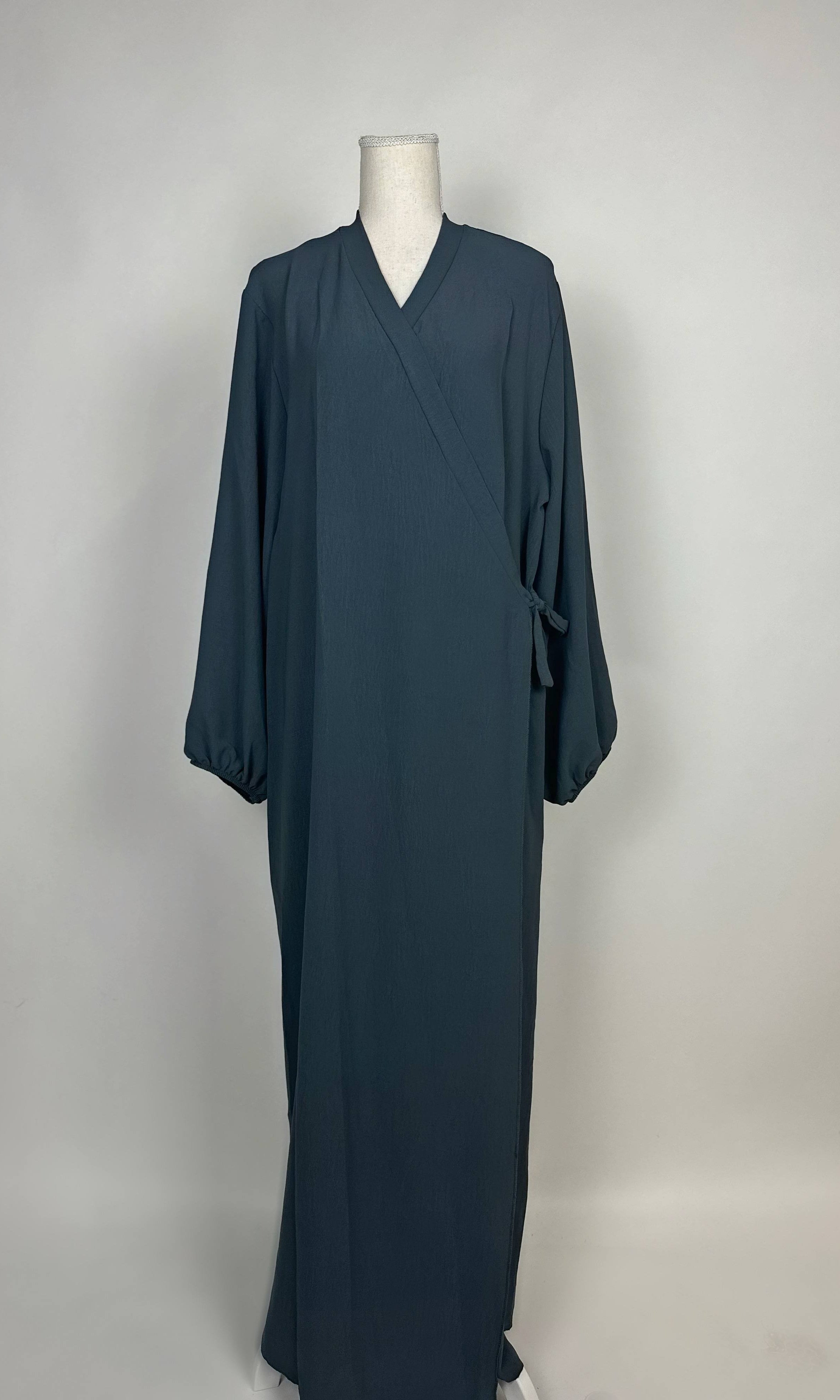 Dunkelpetrolfarbene Wickel-Abaya im Modest-Stil zeigt Ballonärmel und Seitenschleife in Vorderansicht.