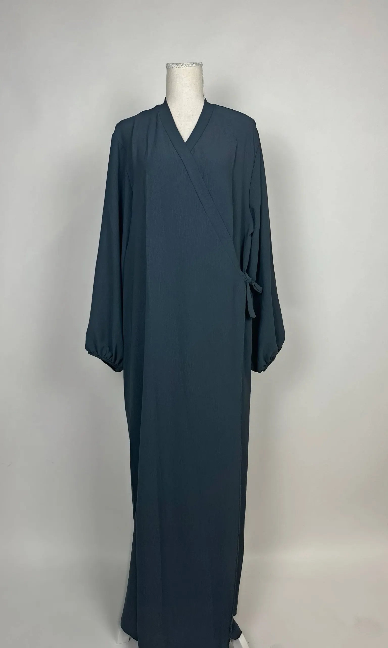 Dunkelpetrolfarbene Wickel-Abaya im Modest-Stil zeigt Ballonärmel und Seitenschleife in Vorderansicht.