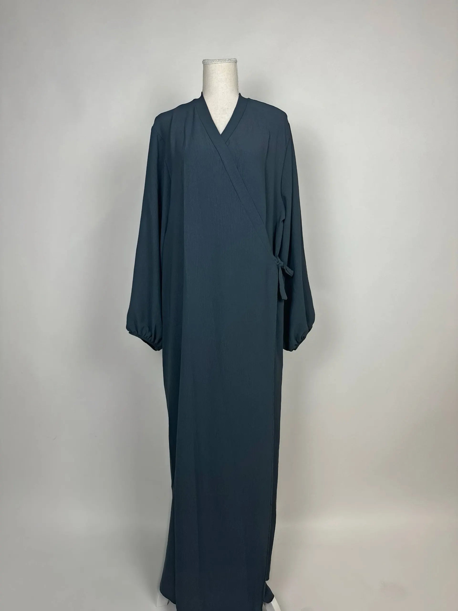 Dunkelpetrolfarbene Wickel-Abaya im Modest-Stil zeigt Ballonärmel und Seitenschleife in Vorderansicht.