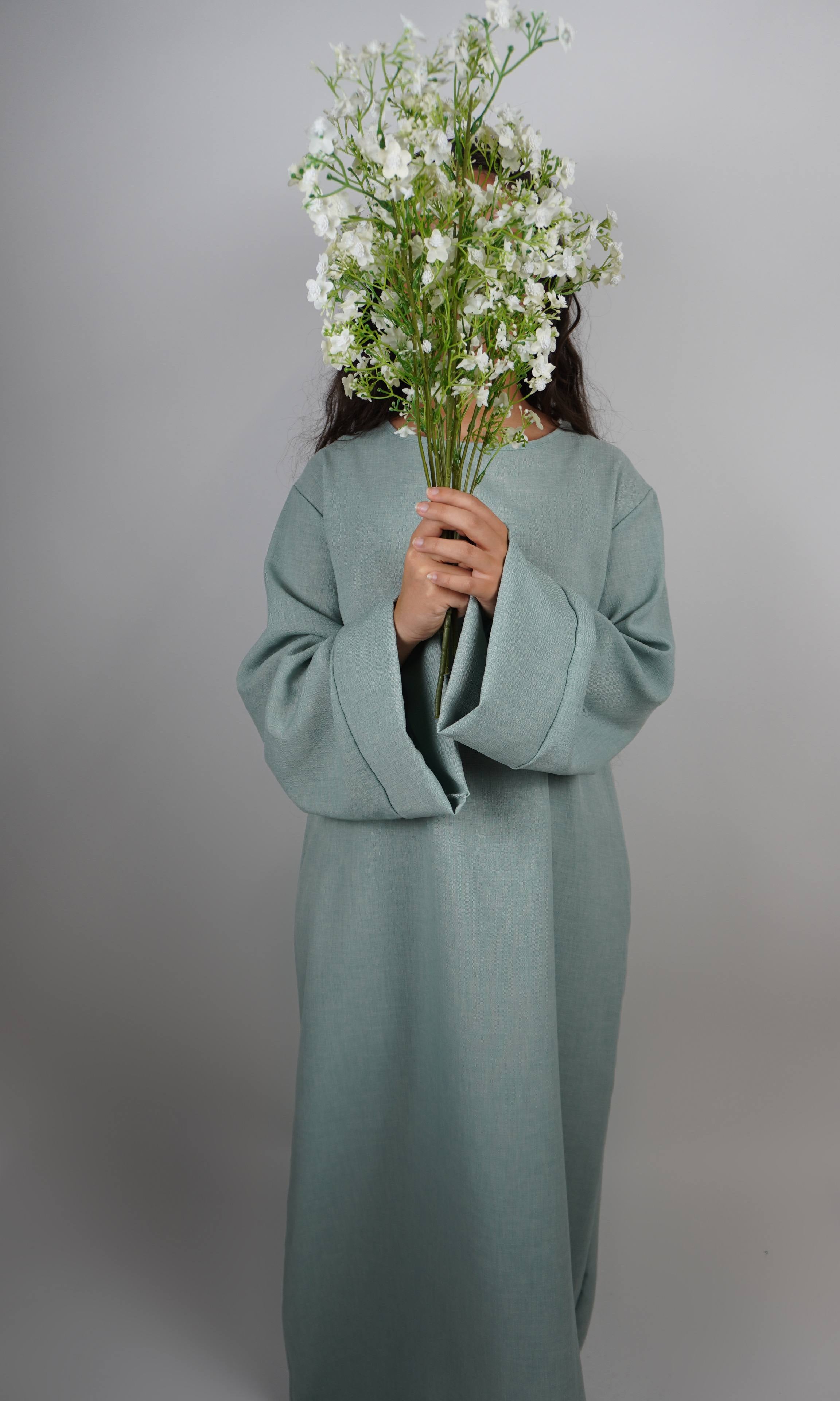 Diese schlichte sandfarbene Abaya in Leinenoptik ist knöchellang und in Frontansicht dargestellt.