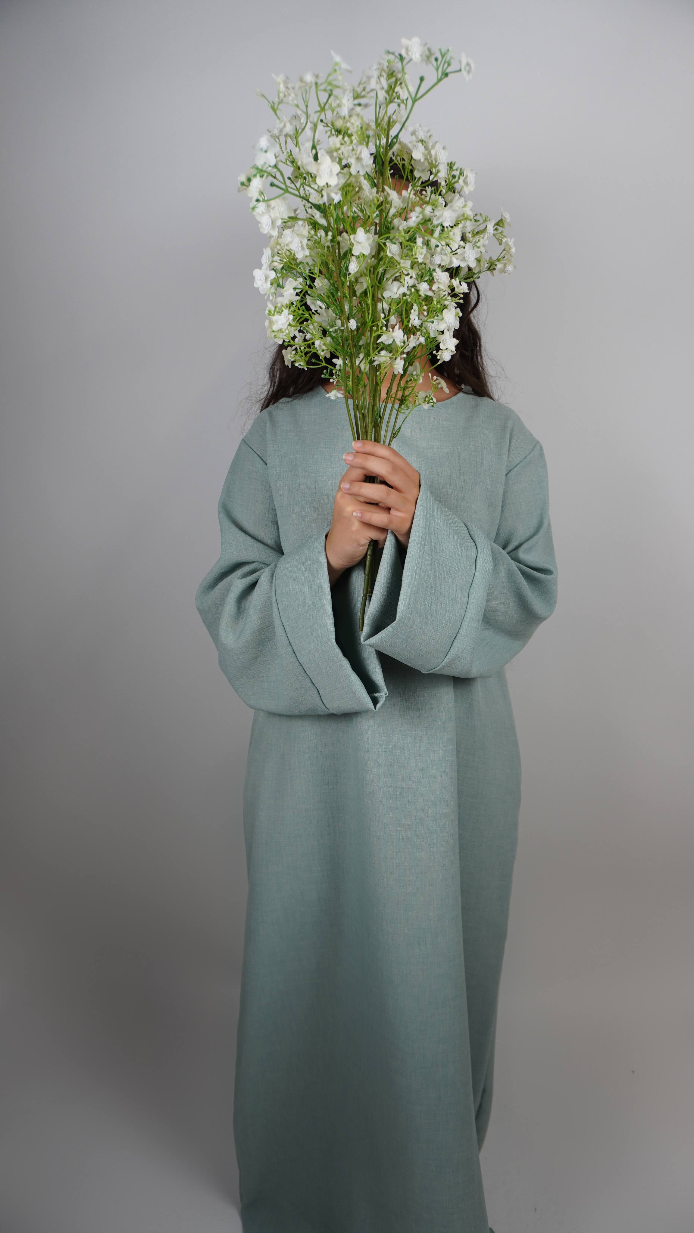 Diese schlichte sandfarbene Abaya in Leinenoptik ist knöchellang und in Frontansicht dargestellt.