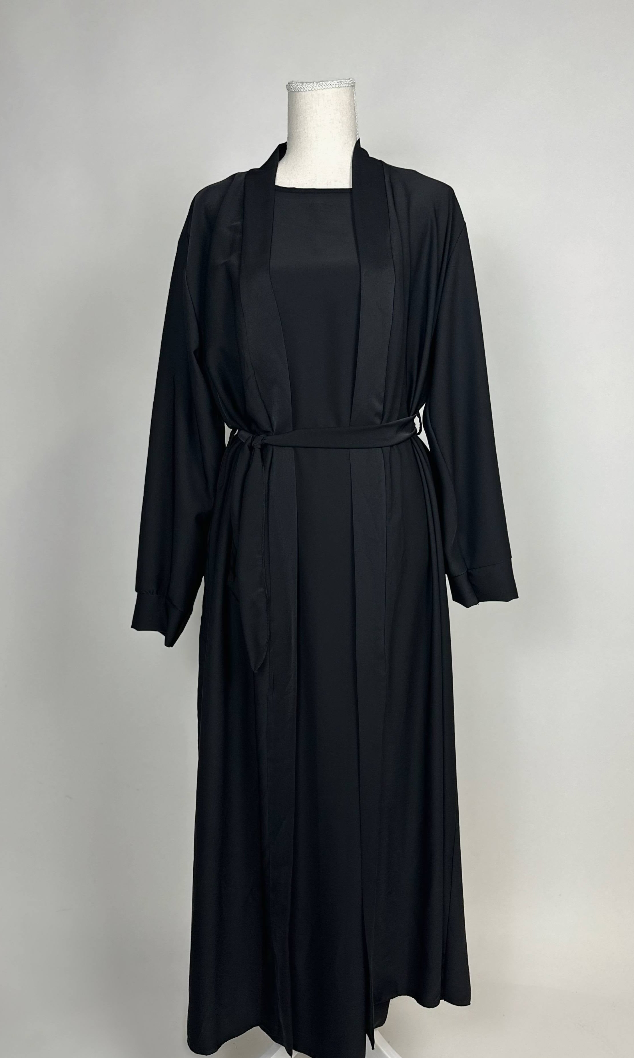 Schwarze Open-Abaya aus fließendem Stoff mit Unterkleid und Bindegürtel, Vorderansicht.