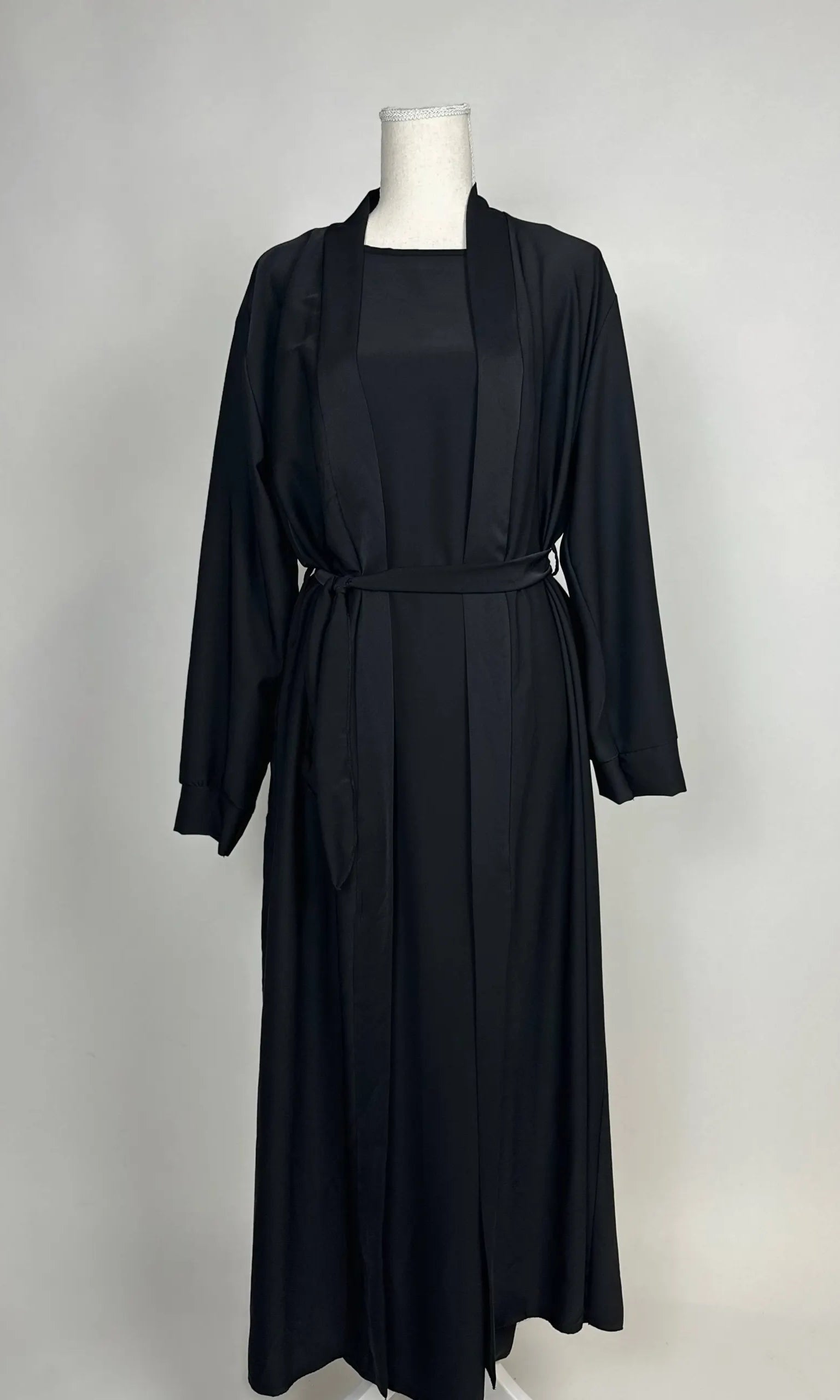 Schwarze Open-Abaya aus fließendem Stoff mit Unterkleid und Bindegürtel, Vorderansicht.