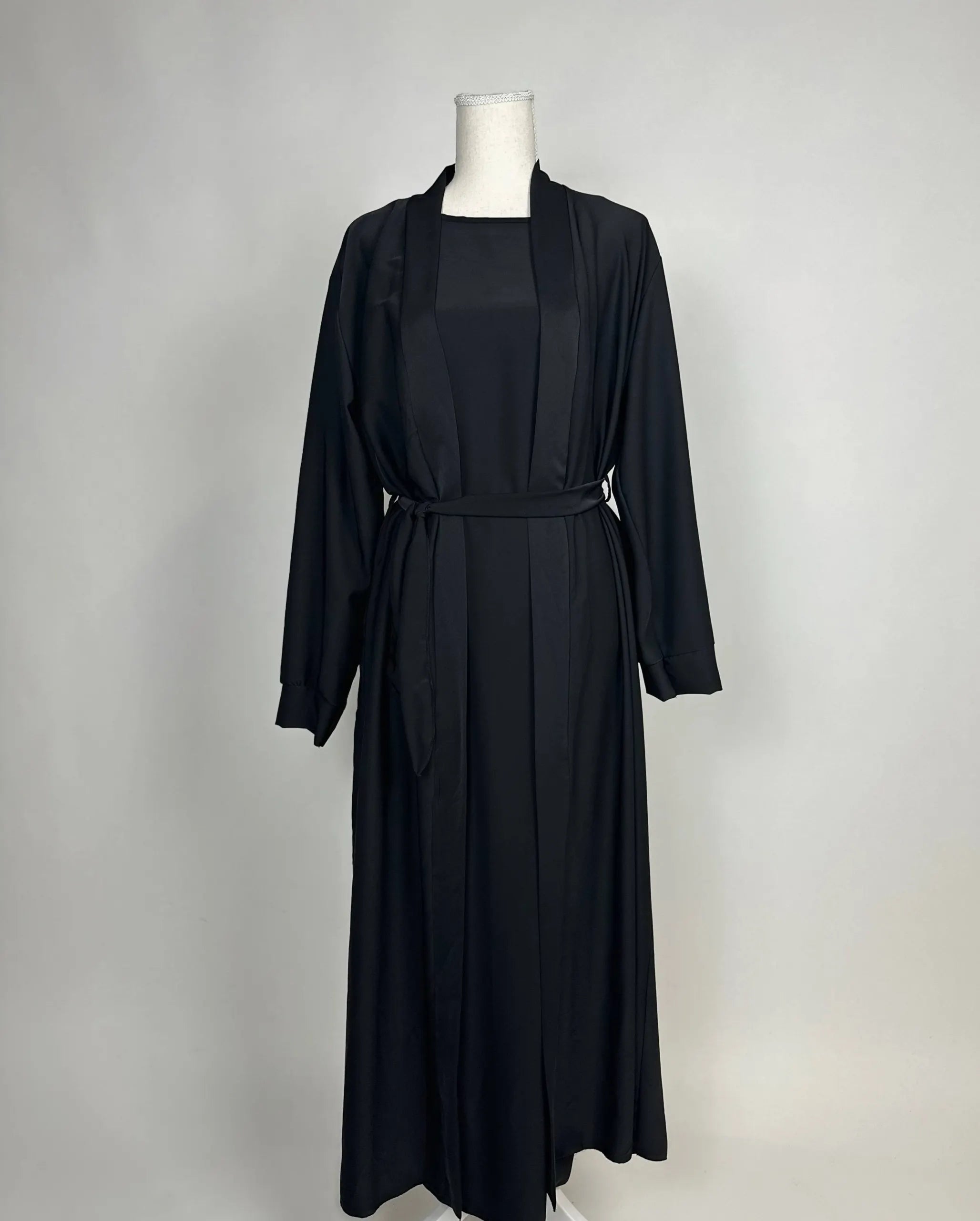 Schwarze Open-Abaya aus fließendem Stoff mit Unterkleid und Bindegürtel, Vorderansicht.