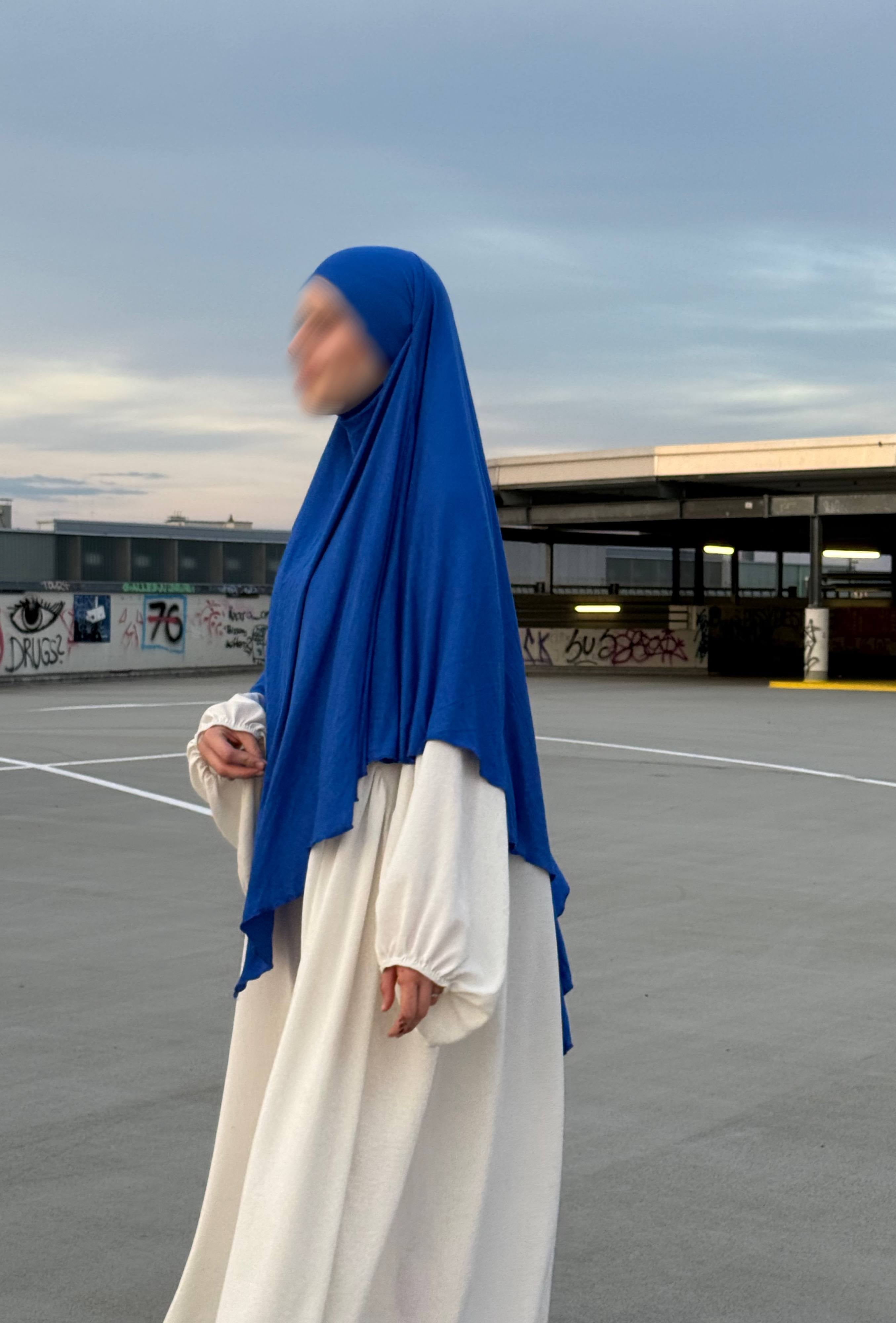 Blauer Jersey-Khimar aus Viskose-Elastan in seitlicher Ganzkörperansicht über weißem Kleid.