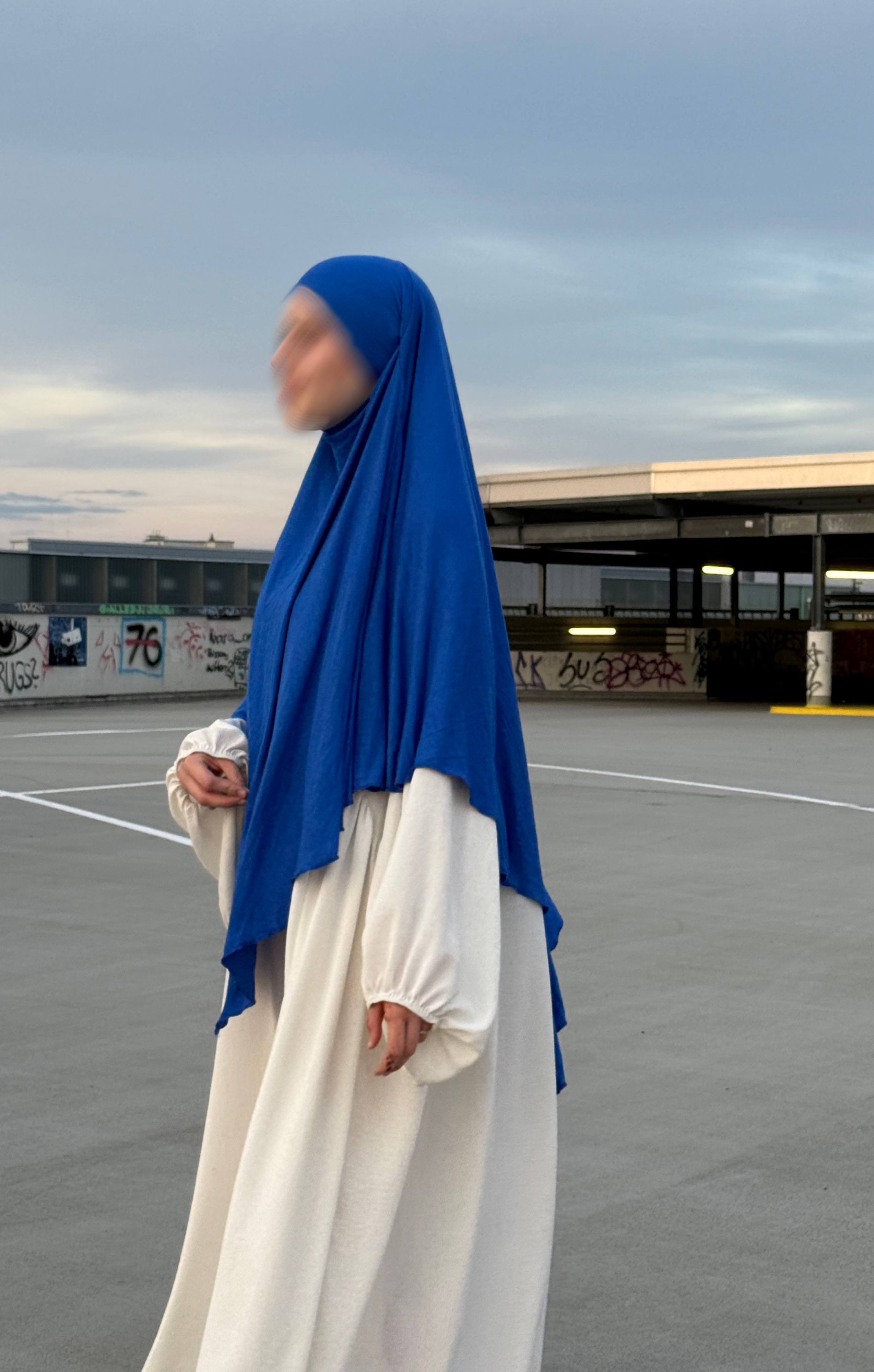 Blauer Jersey-Khimar aus Viskose-Elastan in seitlicher Ganzkörperansicht über weißem Kleid.
