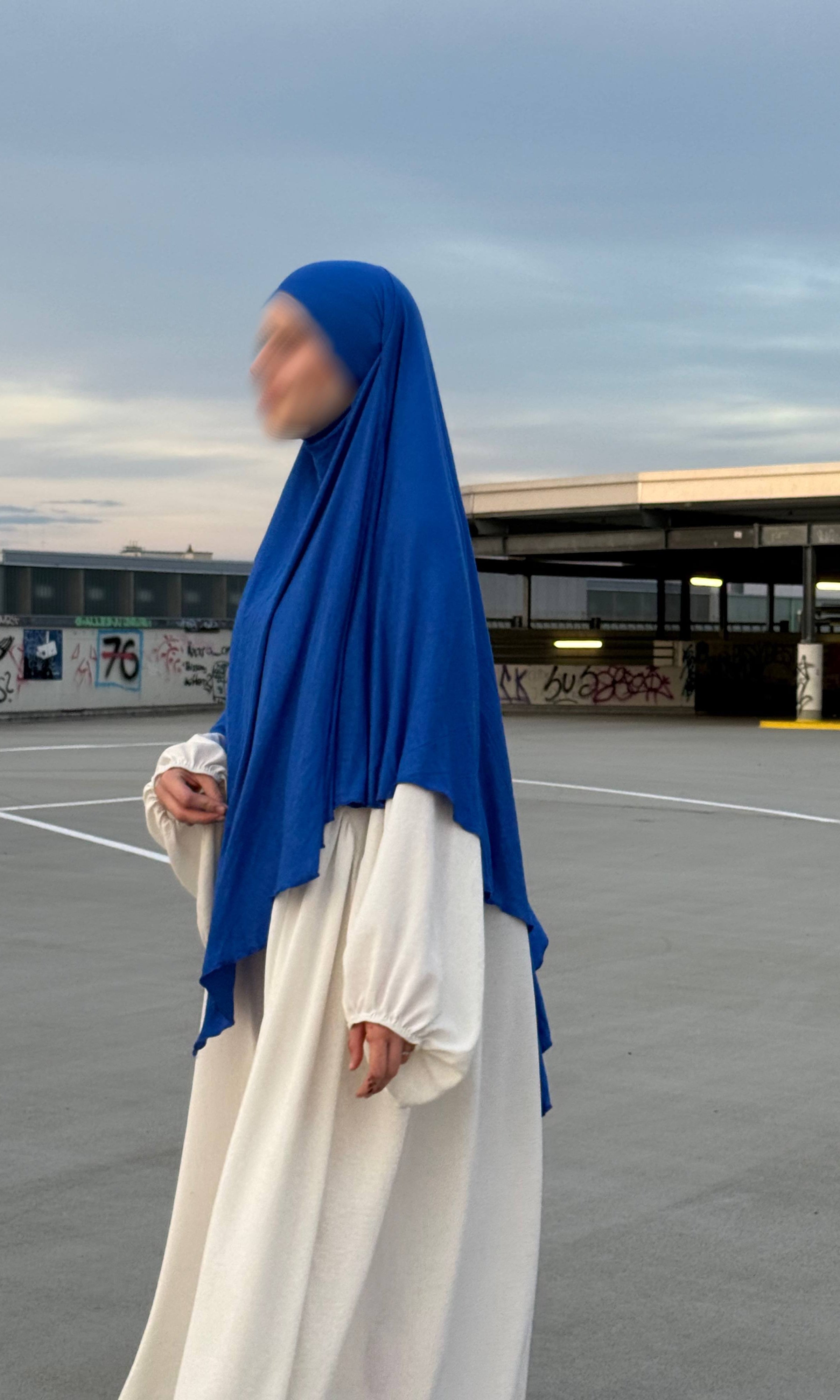 Blauer Jersey-Khimar aus Viskose-Elastan in seitlicher Ganzkörperansicht über weißem Kleid.
