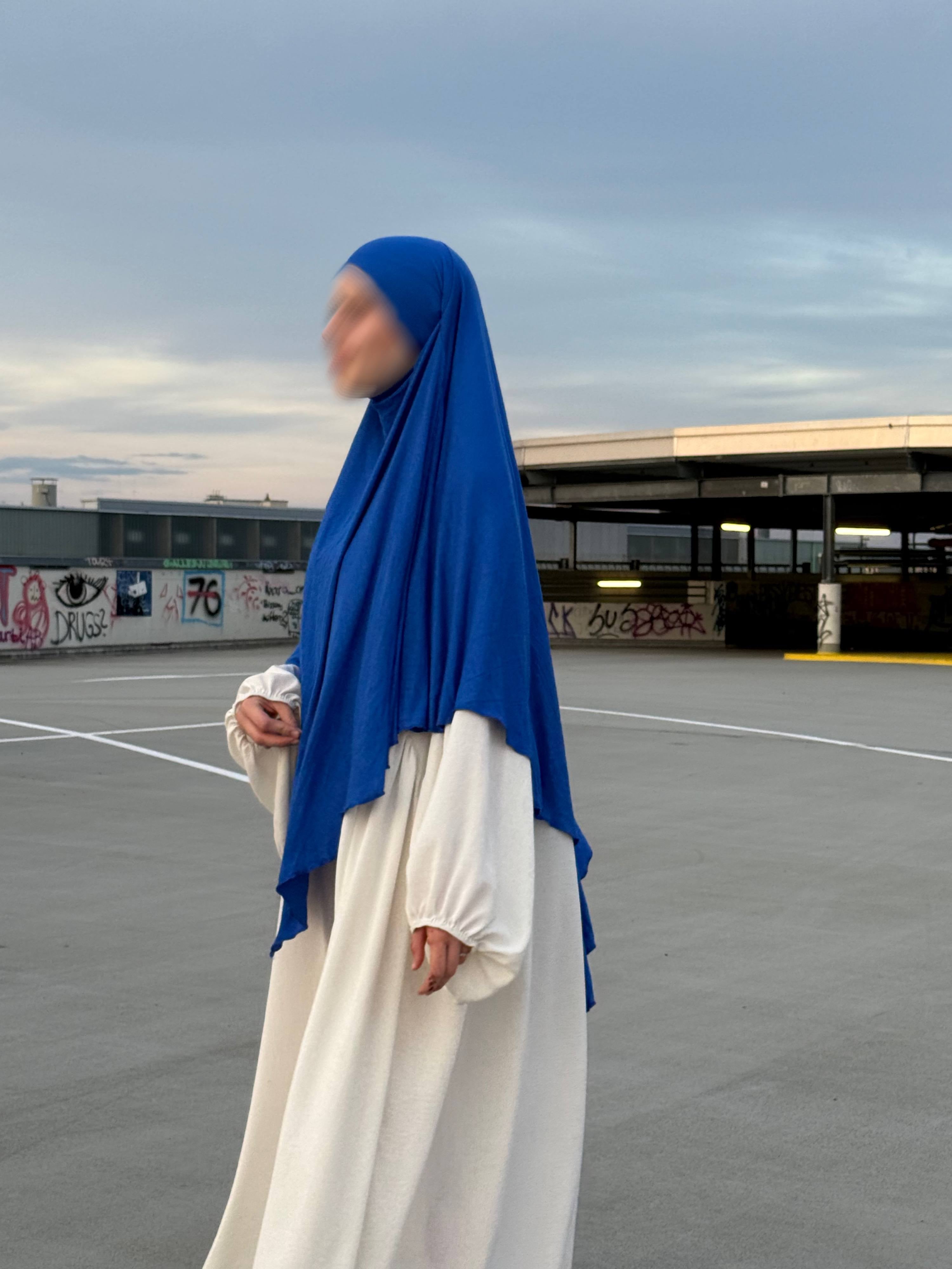 Blauer Jersey-Khimar aus Viskose-Elastan in seitlicher Ganzkörperansicht über weißem Kleid.