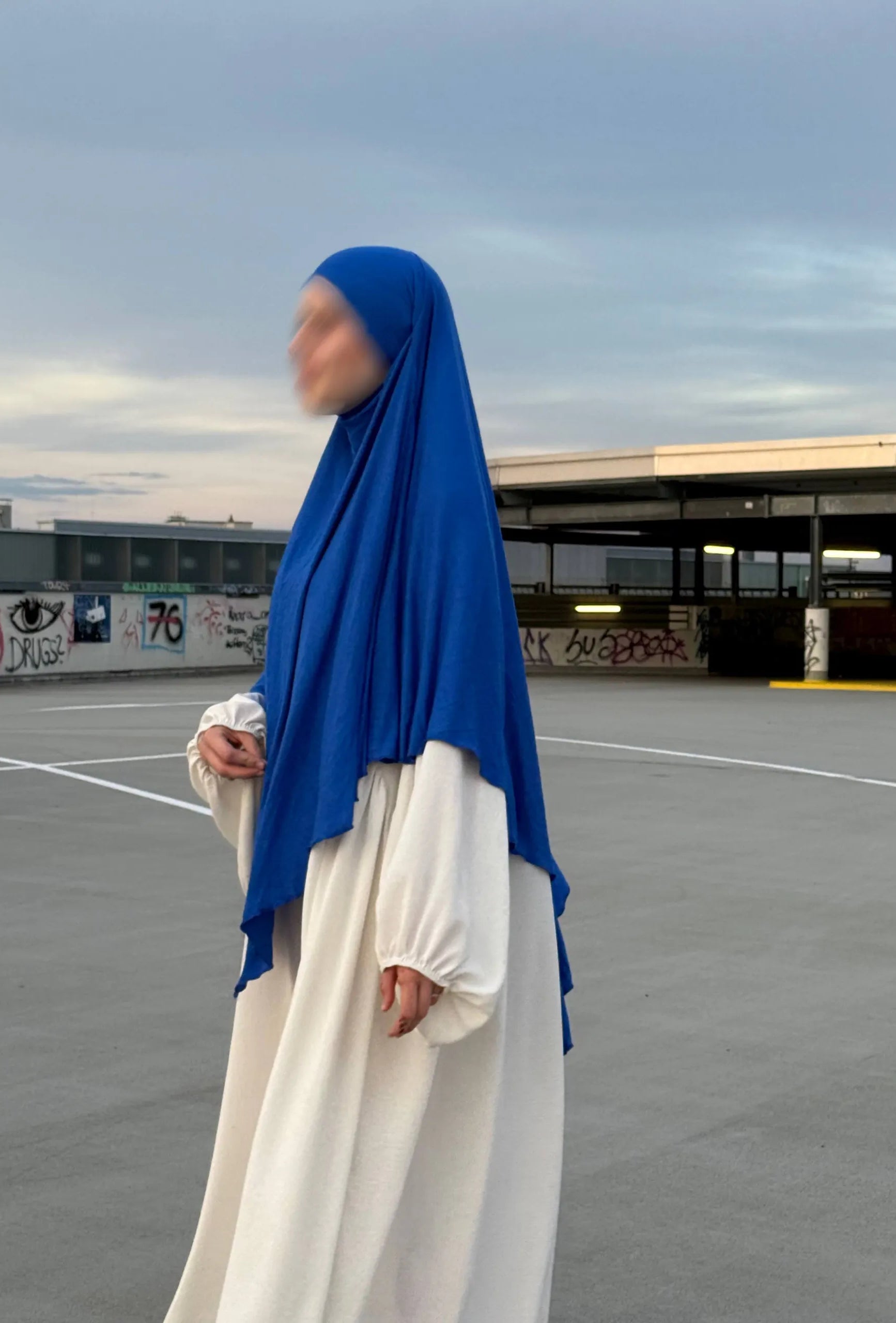 Blauer Jersey-Khimar aus Viskose-Elastan in seitlicher Ganzkörperansicht über weißem Kleid.