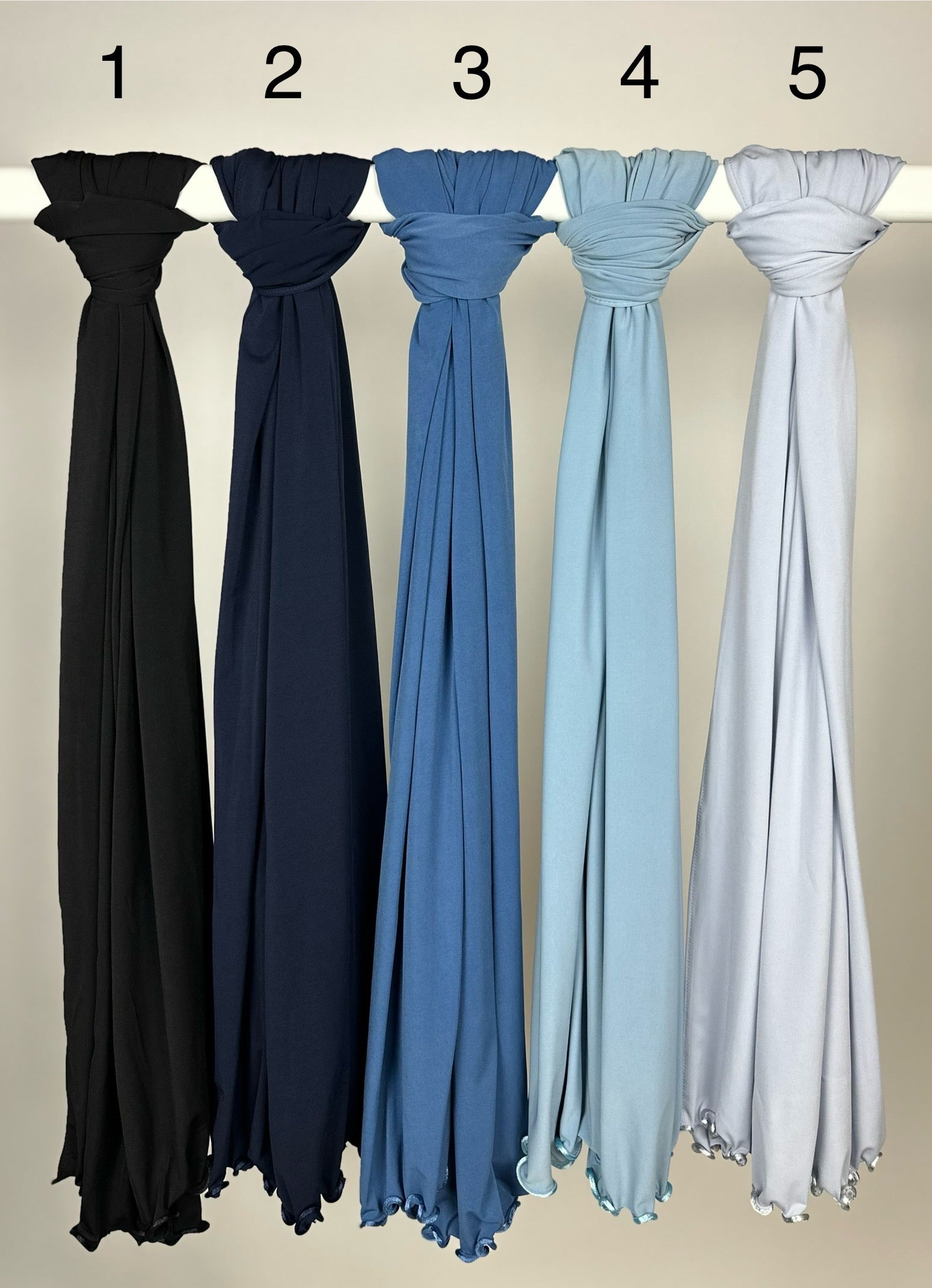 Mehrfarbige Hijabs aus Crinkle-Stoff mit gewelltem Saum, hängend auf Stange, Vorderansicht