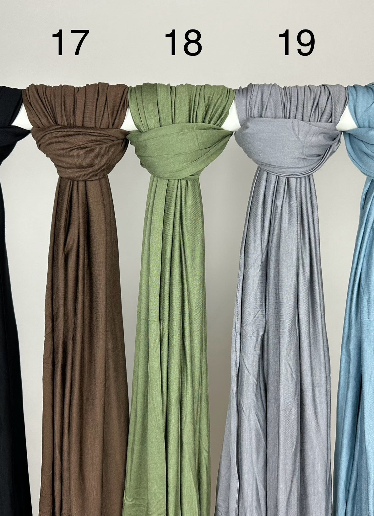 Mehrfarbige Premium-Jersey-Hijabs für Abaya-Modest-Styles hängen weich fallend an einer Stange, Vorderansicht