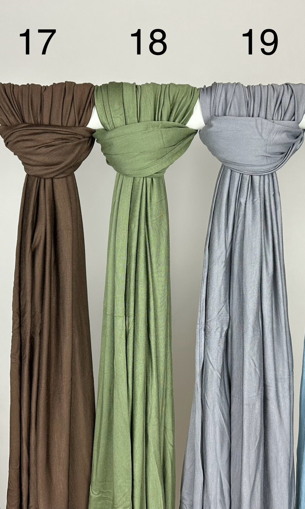 Mehrfarbige Premium-Jersey-Hijabs für Abaya-Modest-Styles hängen weich fallend an einer Stange, Vorderansicht