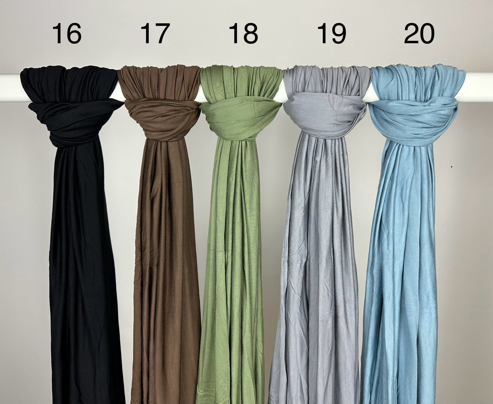 Mehrfarbige Premium-Jersey-Hijabs für Abaya-Modest-Styles hängen weich fallend an einer Stange, Vorderansicht